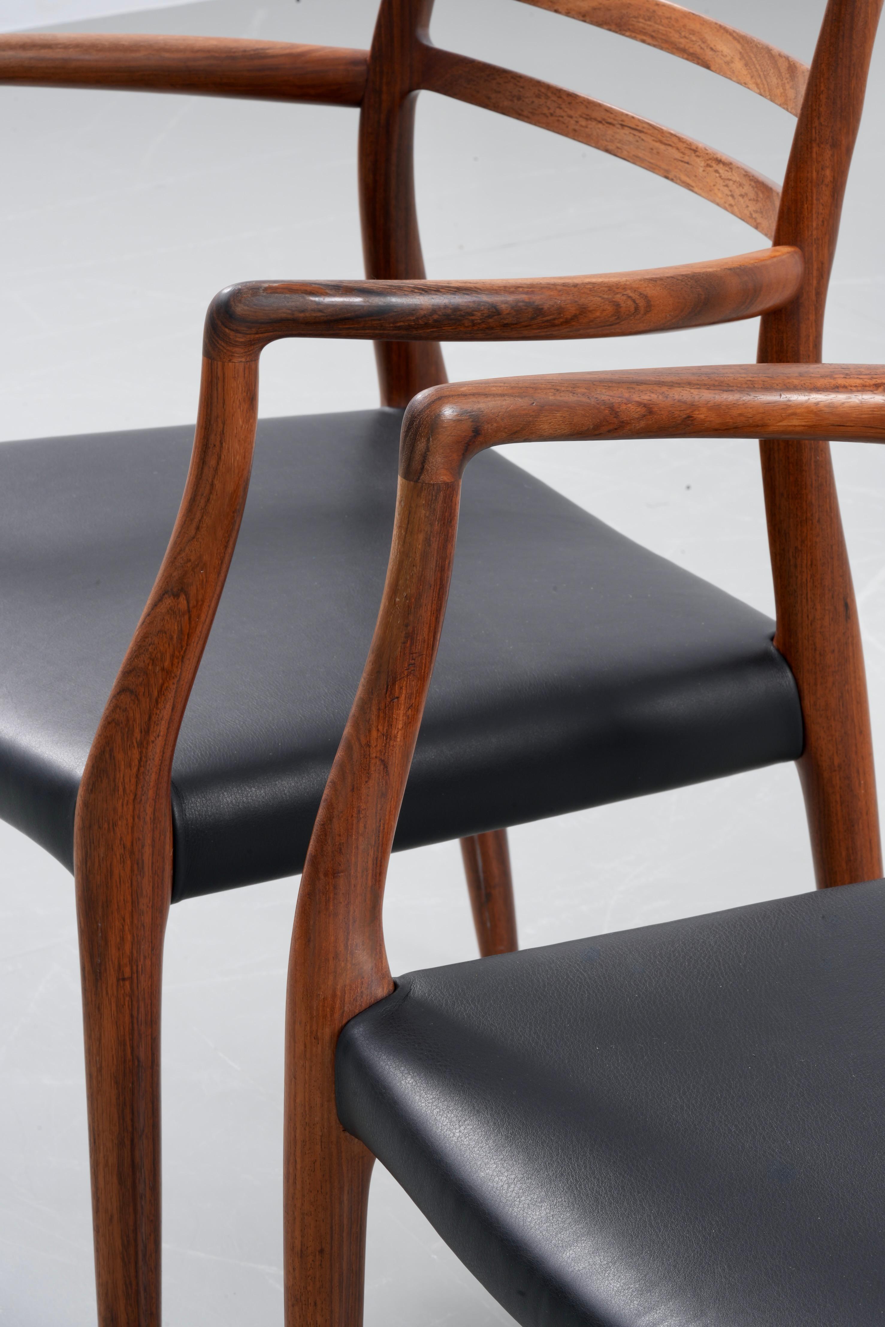 Set of 2 Niels Otto Møller Armchair Model 62, produced in rosewood by J.L. Møllers Møbelfabrik, showcases the quintessential elegance of Scandinavian design. This iconic armchair features a sleek, curved wooden frame, meticulously crafted for