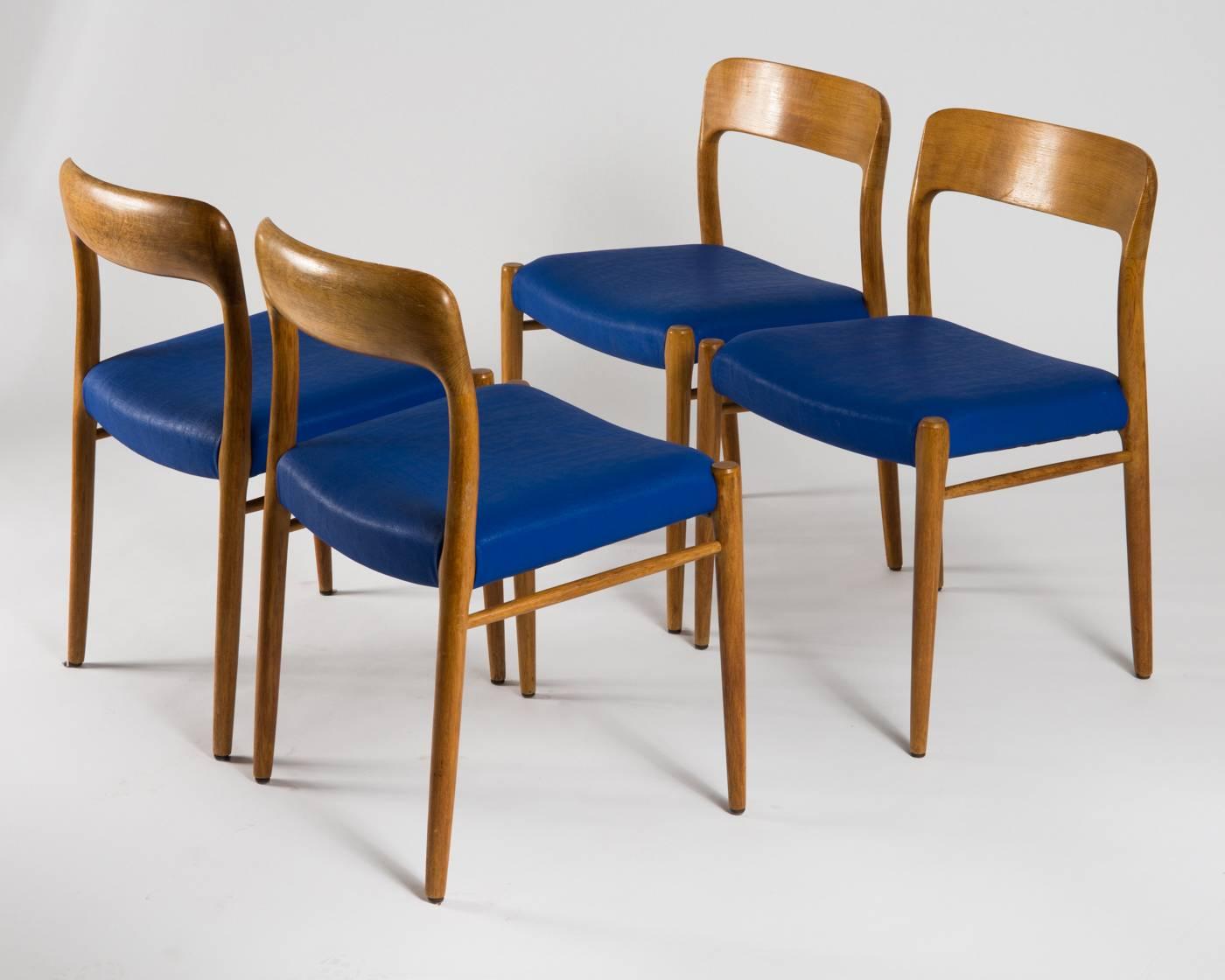 Set of four beautiful dining chairs in solid oak model 75 designed by Niels Otto Møller and manufactured by J. L. Møller. One of N.O. Møller's most coveted designs with its elegant and organic shape. The oak shows a nice golden brown patina achieved