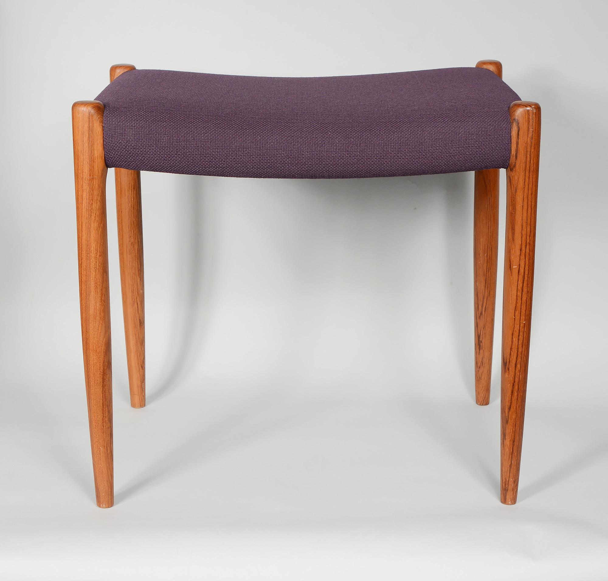 Model 80a stool designed by Niels Otto Moller and manufactured by J.L. Moller of Denmark. This has teal legs with an upholstered seat. The upholstery is possibly original but may be an older reupholster. The wool fabric is in good condition. This