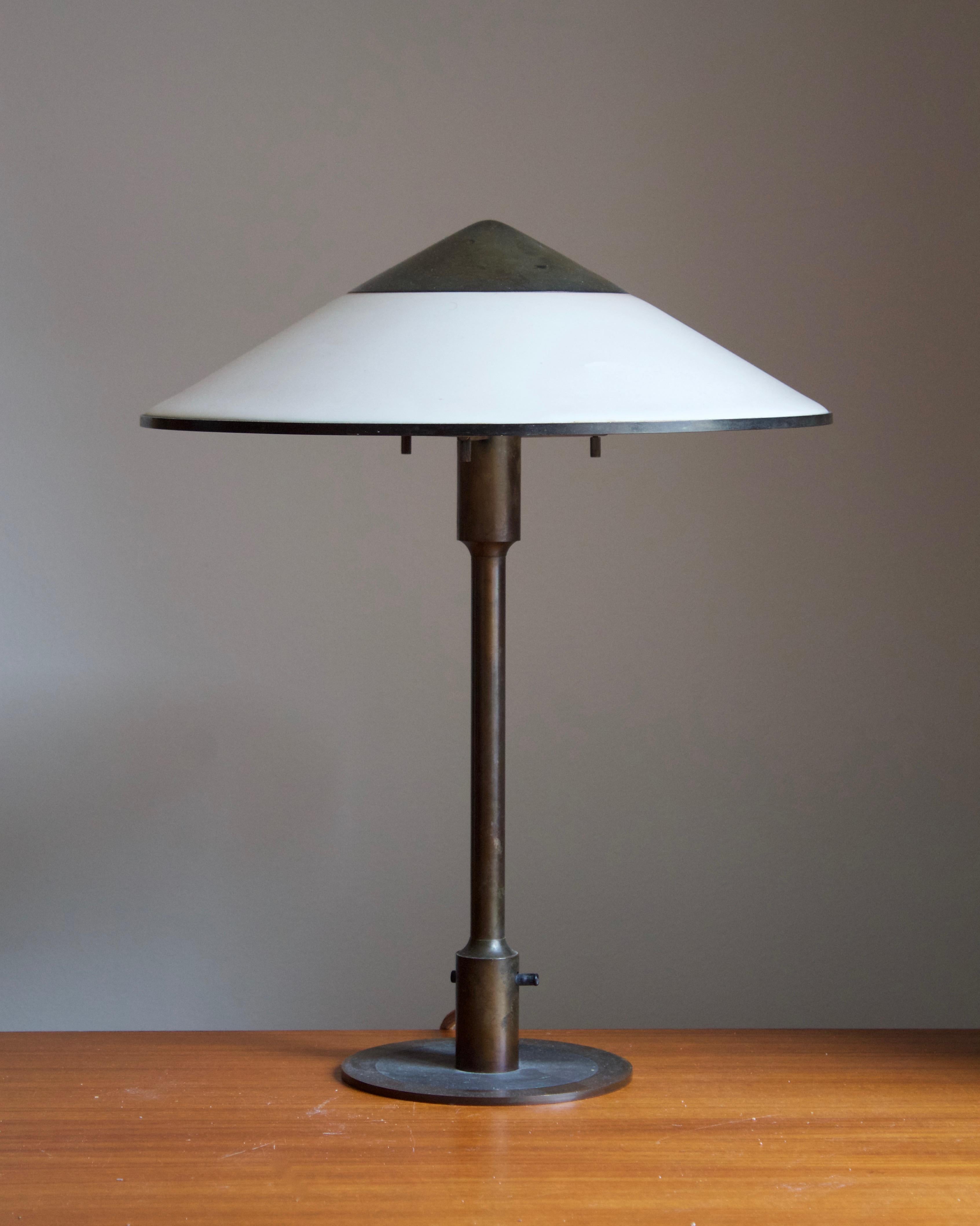A rare and early table lamp / desk light. Designed by Niels Rasmussen Thykier for Fog & Mørup, Denmark, 1930s. Features a break-through switch typical to early production examples.

In patinated brass and waxed paper screen.

