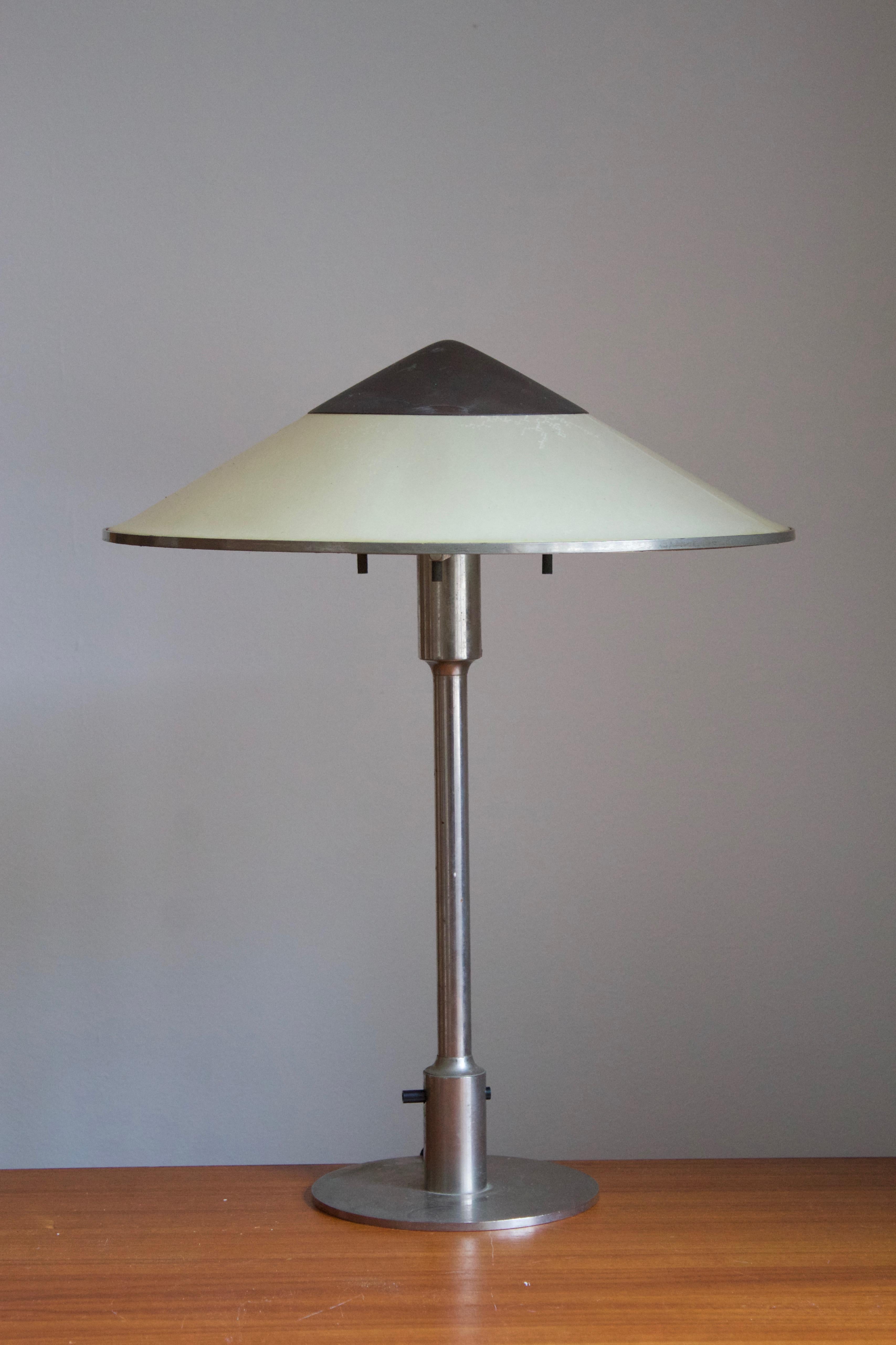 A rare and early table lamp / desk light. Designed by Niels Rasmussen Thykier, Denmark, 1930s. Features a break-through switch typical to early production examples.

In nickeled brass and waxed paper screen.

 