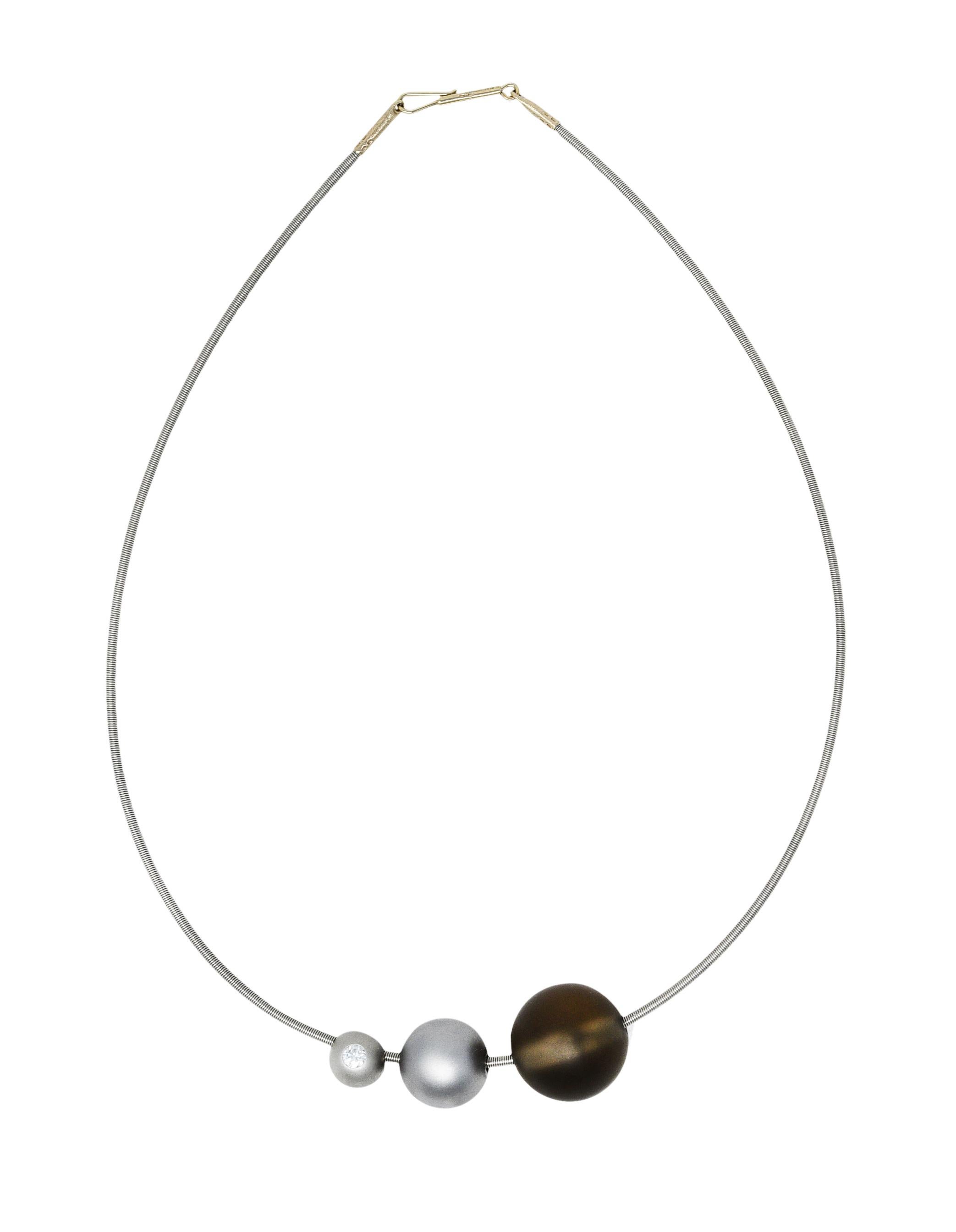 Collar necklace designed as coiled platinum chord strung with three spherical beads graduating in size

Two smaller beads are matte finish platinum and range in size from 9.0 mm to 14.0 mm

Smaller bead centers a flush set round brilliant cut