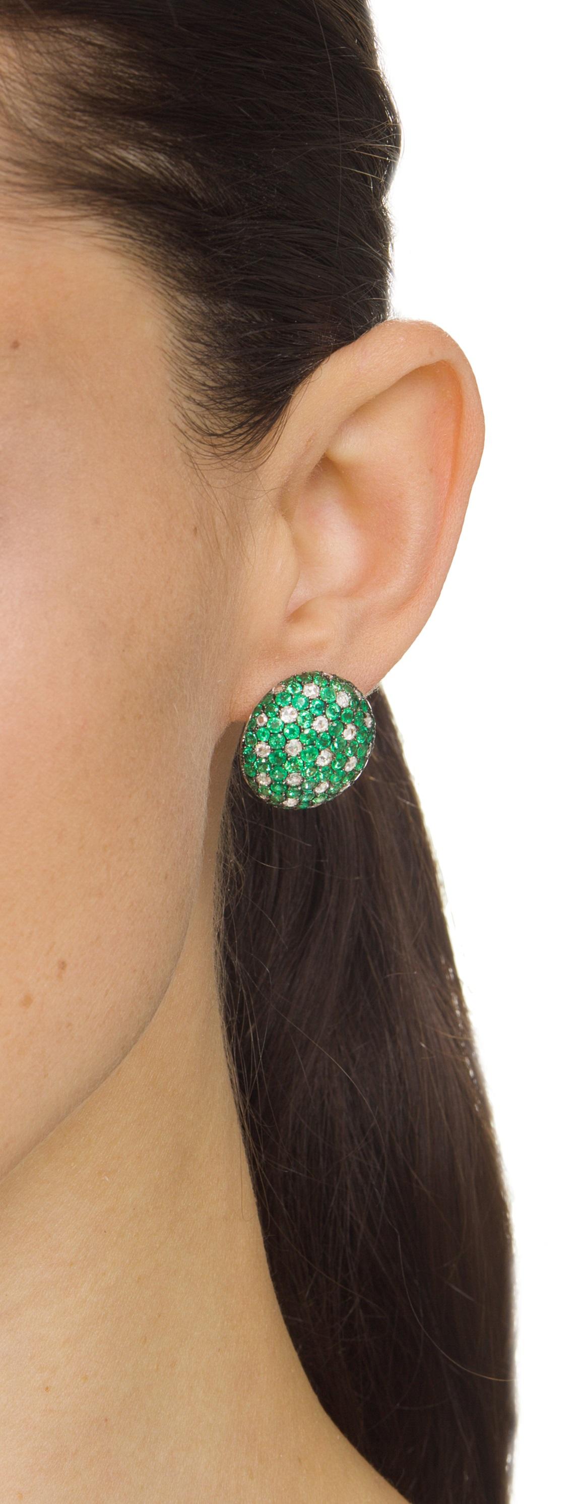 Der wunderschöne Ohrring hat einen modischen Look, der von Nigaam in einem schillernden Kreis aus 18 Karat Weißgold in schwarzem Rhodium eingefasst und mit einem runden Diamanten von 2,00 Karat und einem runden Smaragd von 6,35 Karat gestaltet