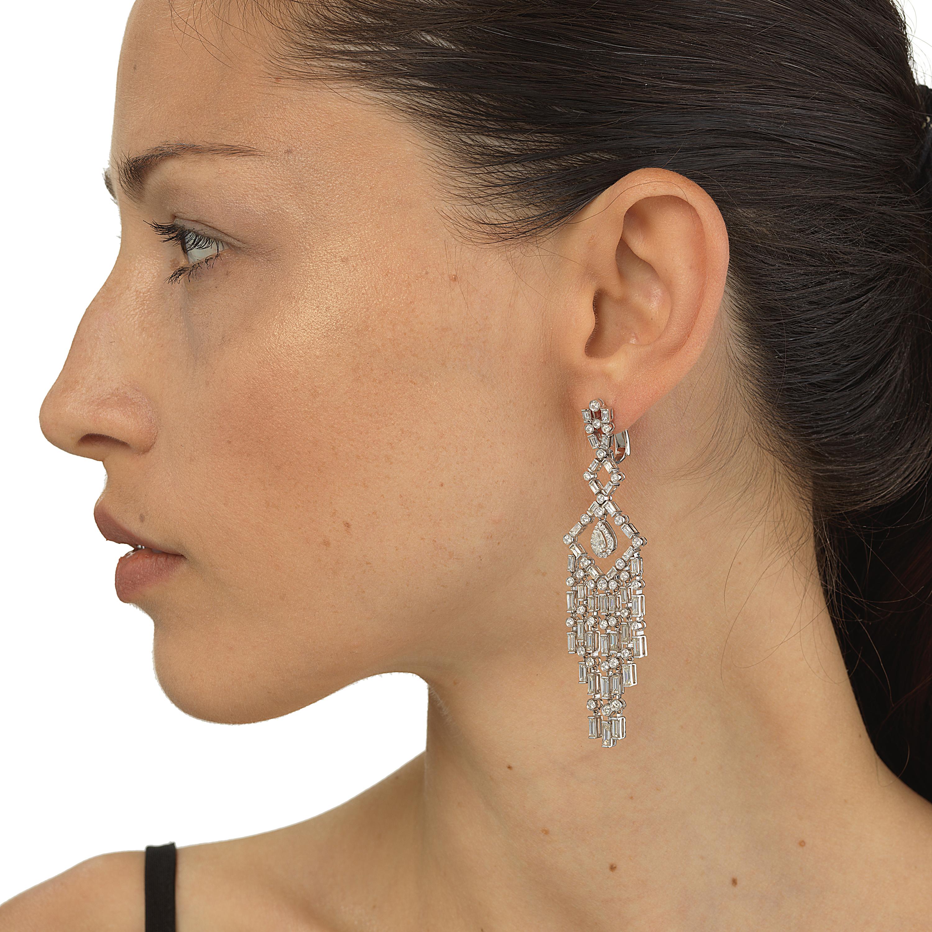 These diamond chandelier drop earrings by Nigaam are embellished with smaller and larger diamonds. This chandelier earring features pear cut diamond in the center enclosed in a halo of pave diamond mounted on white gold. seven graduating stands of