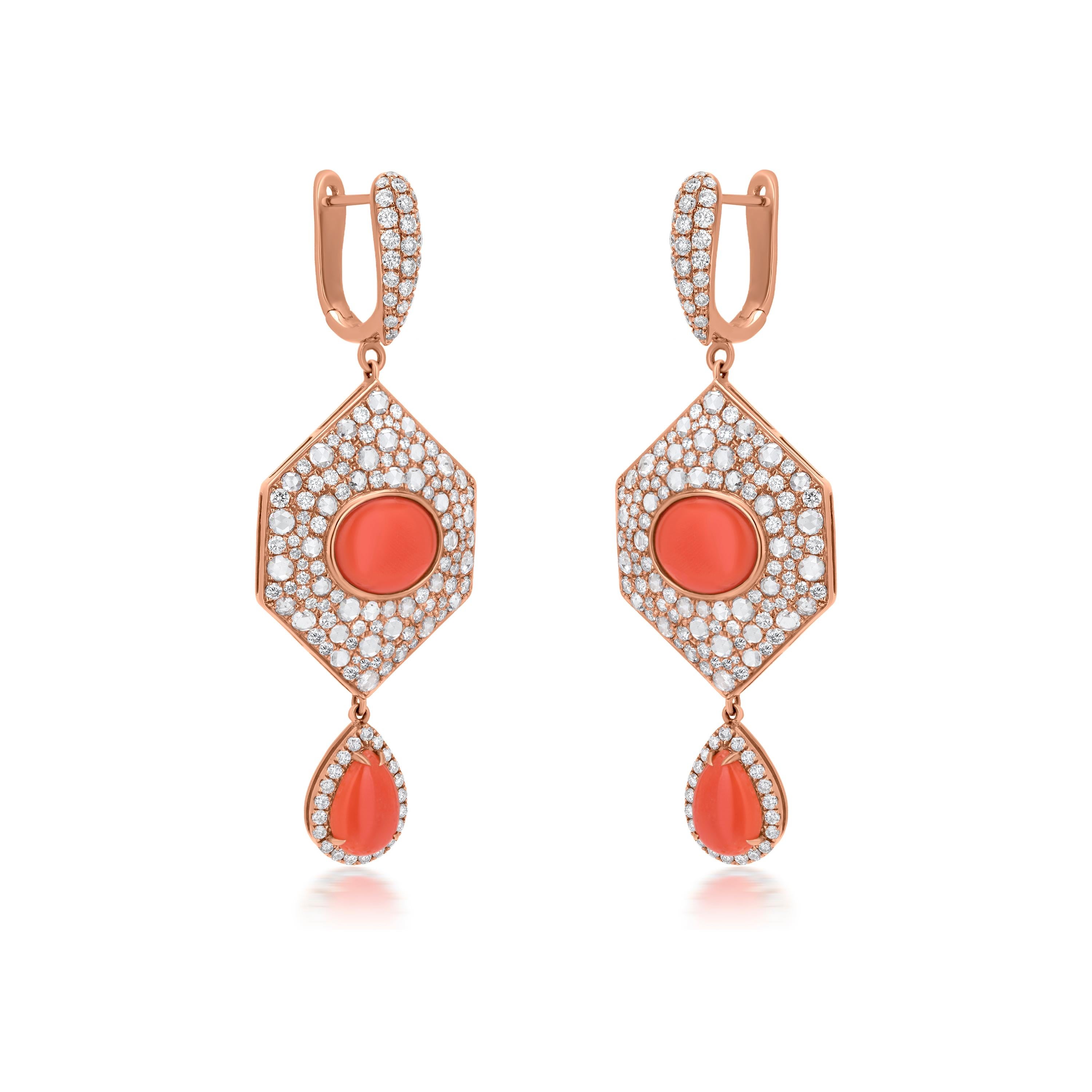 This Nigaam 18K Rose Gold earring has water-drop-shaped lower danglers featuring two pear-cabochon Red Coral stones in a prong setting, weighing 2.06 Cts. The center body of the earring looks like two glistening hexagonal diamond studded plates