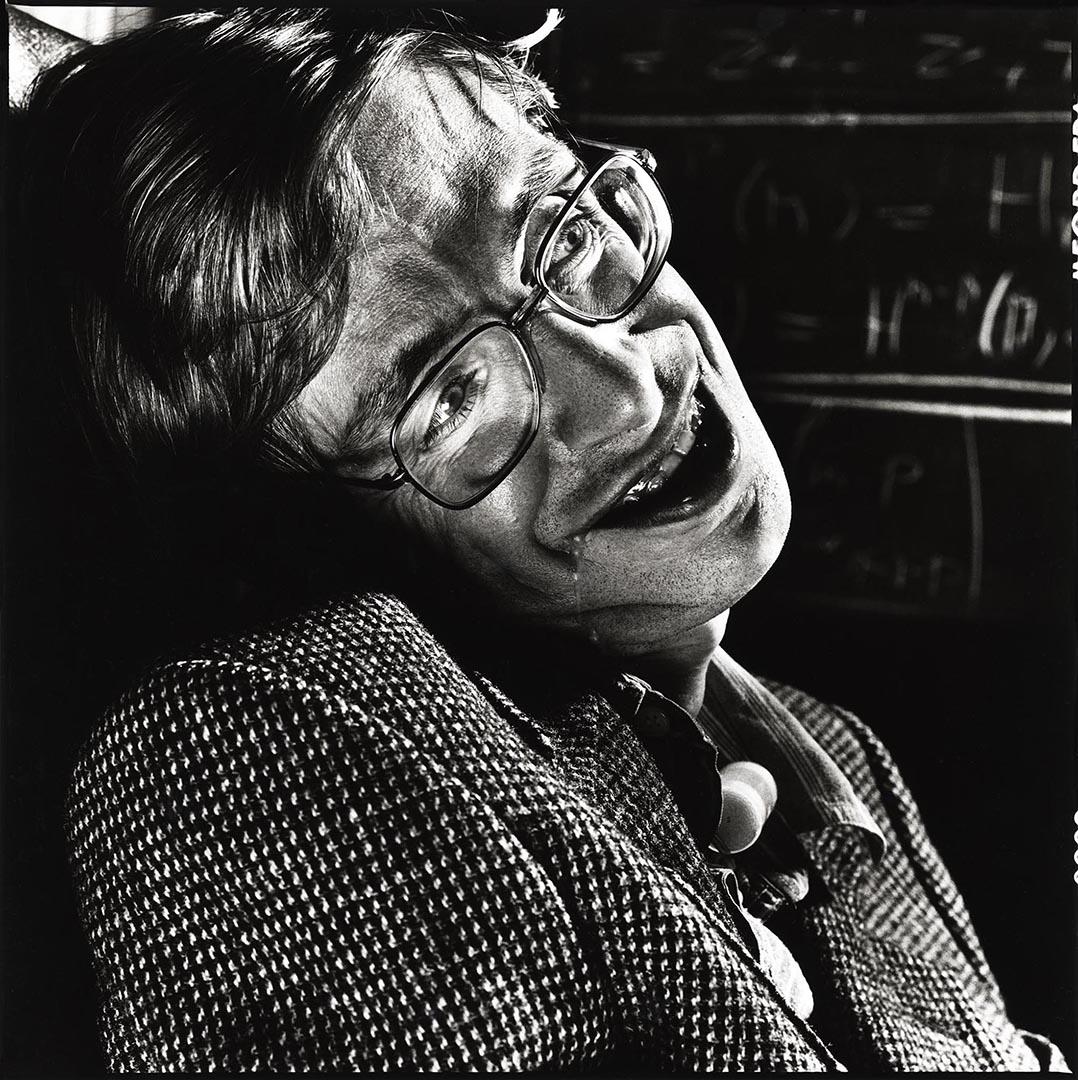 Nigel Parry’s portrait of Professor Stephen Hawking reveals both intellect and humanity in equal measure. Shot in stark black and white, the composition draws the viewer directly toward Hawking’s expressive gaze and unmistakable presence. Rather