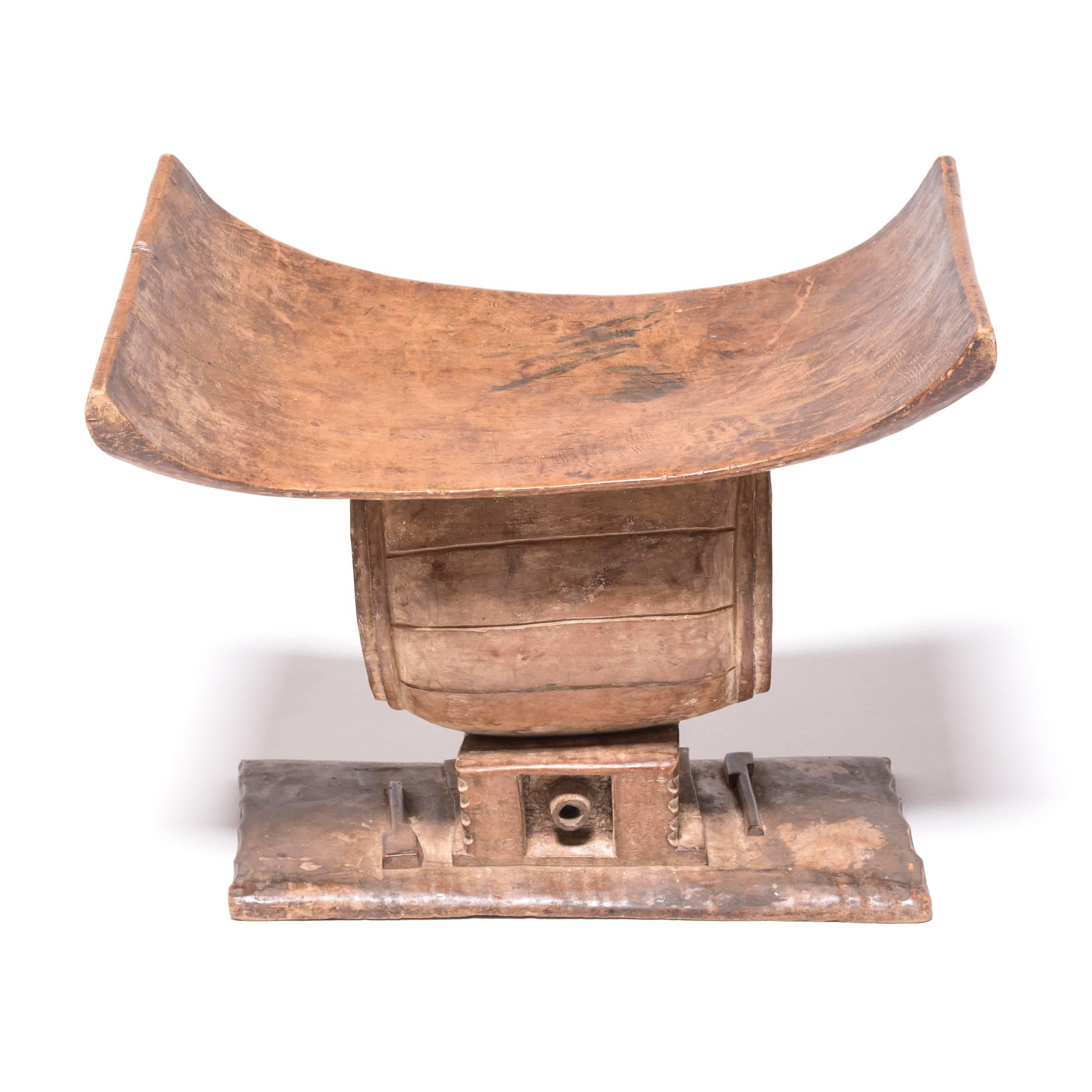 In traditional Ashanti culture, stools indicated power, status, and lines of succession. The flat base, curved seat, and ridged supports of this piece reference the Ashanti King Stool. While most Ashanti woodworkers carved the central support into a