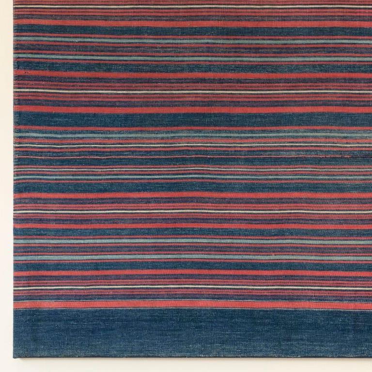 Una tela muy poco habitual tejida en tonos azules con rayas coral y marfil.
Este tipo de tela se teje para celebrar la mayoría de edad de las niñas del pueblo.
Conservación montada en camilla.
Aldea de Ososo. Edo, Nigeria Años 30
Alto 86 x Ancho 145