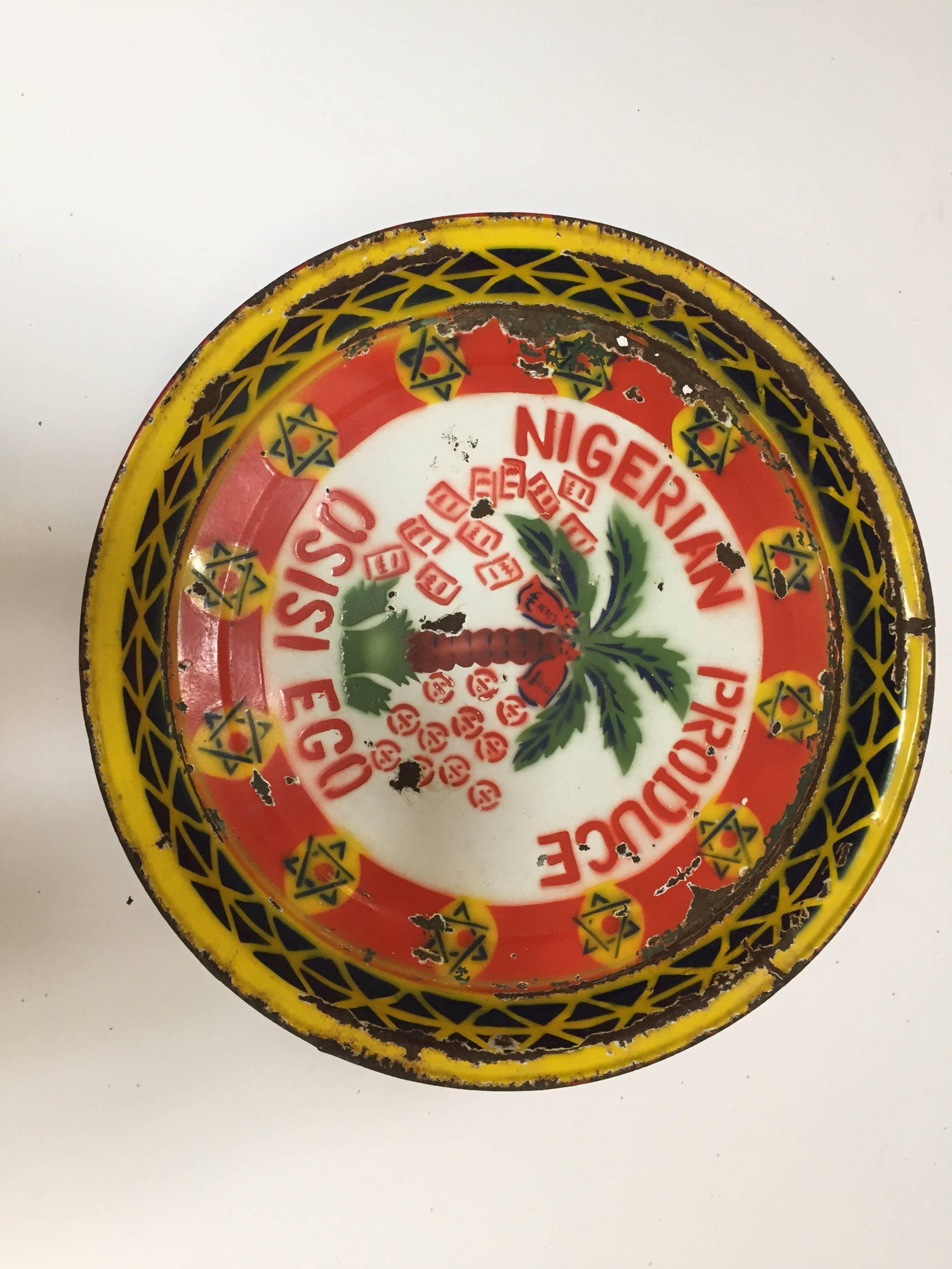 Nigerian metal vintage advertising platter plaque.
Great African Folk Art advertising from Niger.
Round large metal plate in red and white, green and yellow primary colors with a design of a palm tree, cocos and inscription of 