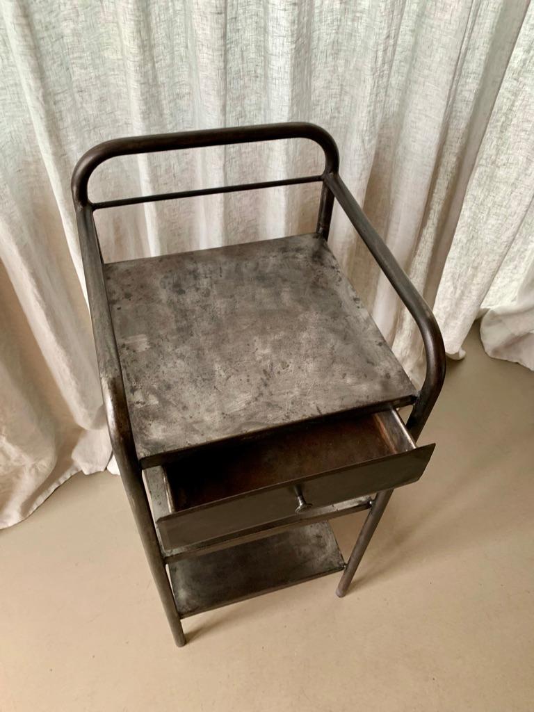 Vintage French metal night stand or side table with the greatest patina in the raw metal. The night stand has one drawer and 2 shelves.