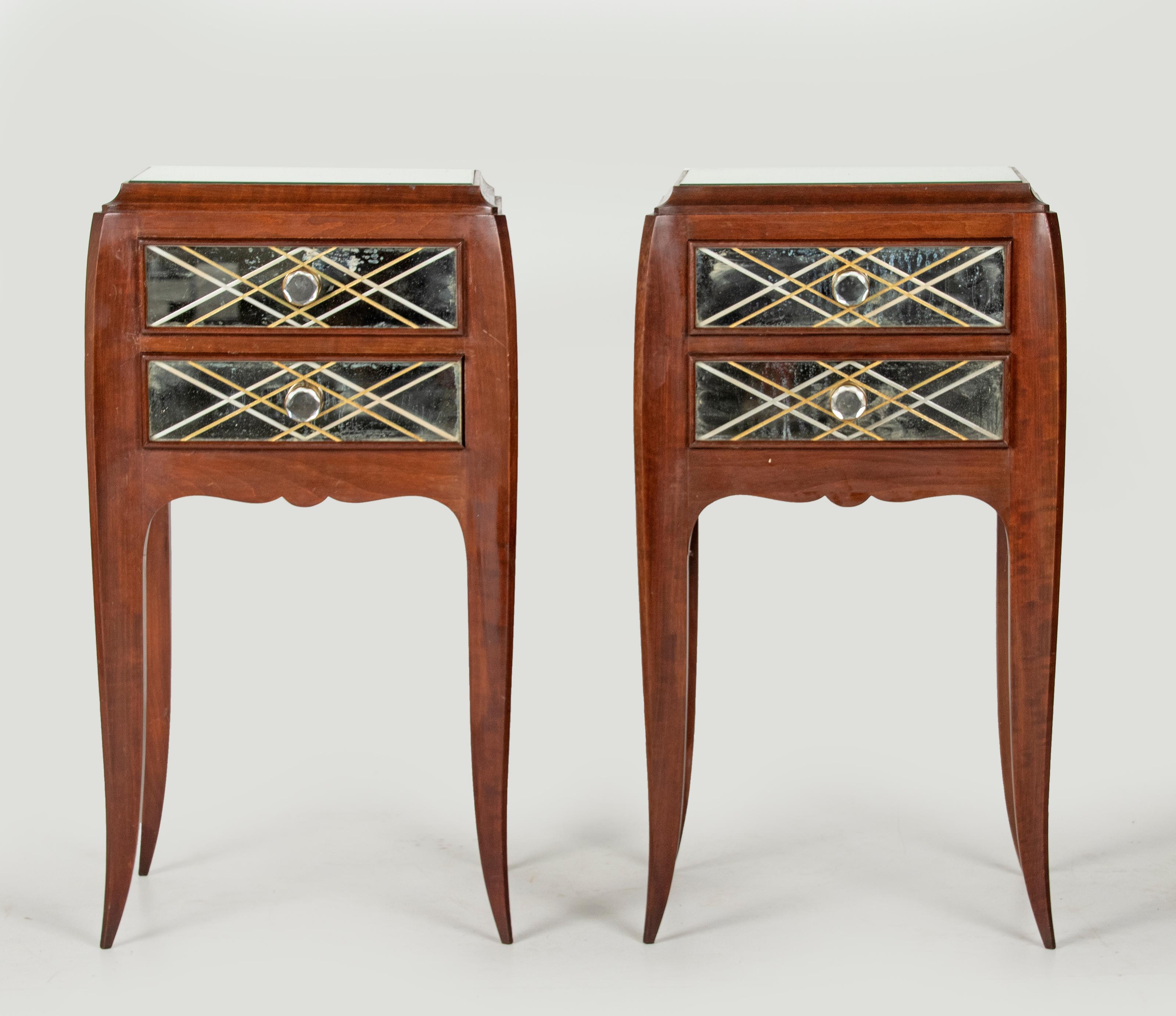 A pair of mahogany side tables / nigtstands. In the style of the French designer Jean Pascaud. The tables have each two drawers, with mirror glass fronts and knobs. Engraved diamond motif pattern with gilt accents. On top of a mirror glass. Elegant