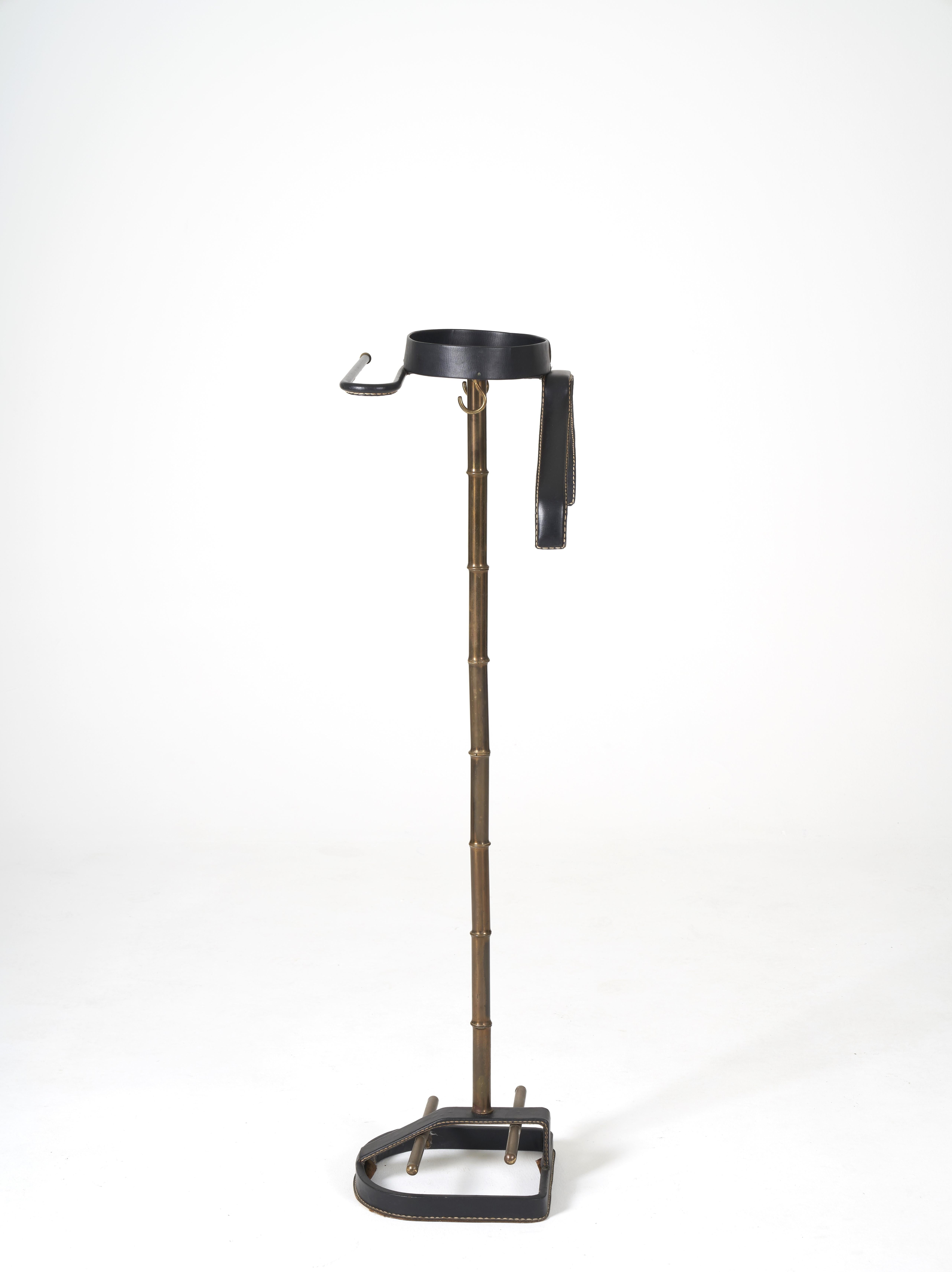 Nightstand Jacques ADNET for the Compagnie des Arts Français, 1950s. Base in gilded tubular metal imitating bamboo. Shelf, coat rack and trouser bar in sewn black leather. Shoe bar in brass. Good condition.
