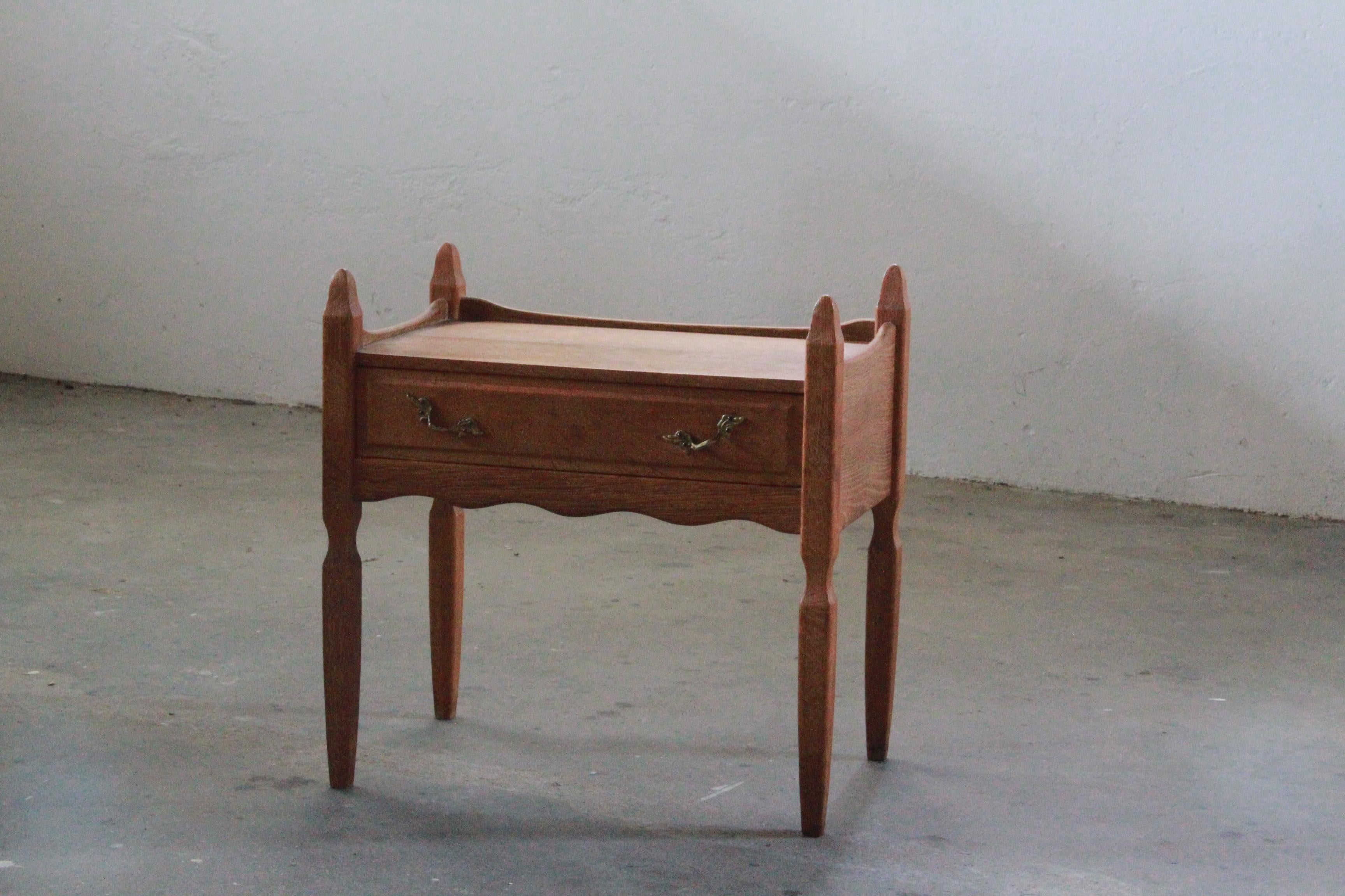 Presenting a oak bedside table attributed to Henning Kjærnulf, crafted in the 1960s by Nyrup Møbelfabrik. In good vintage condition, this nightstand exhibit a poetic blend of baroque and modern design. This rare sculptural, baroque, brutalist table