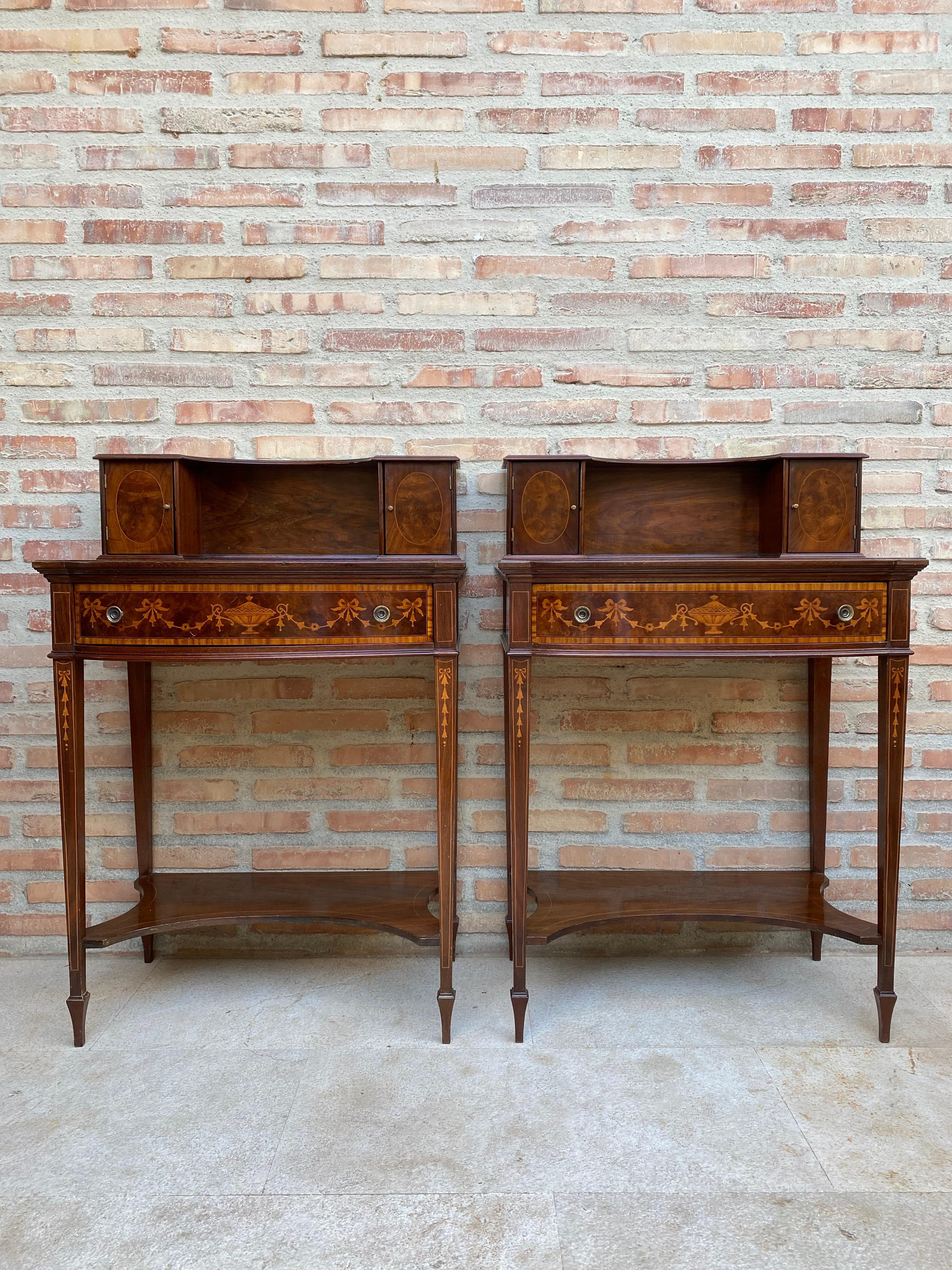 Pair of nightstands or secretary desk with French marquetry on the top, each one slightly oval in shape with a central drawer that has two bronze handles and frontal marquetry. On the top of the tables we find a small open shelf with two small