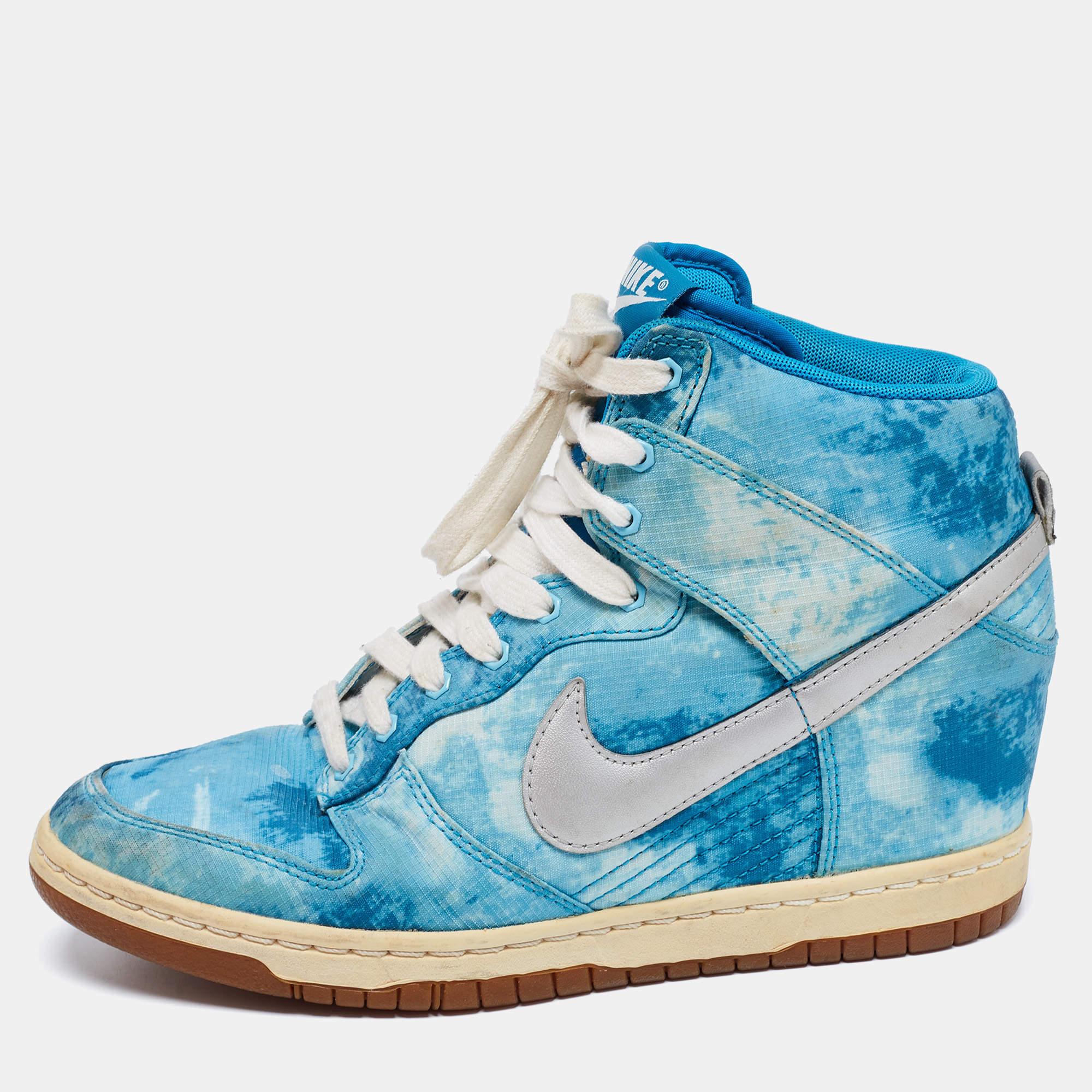 These Nike SB Dunk high top sneakers for women have a watercolor canvas exterior with the Swoosh in leather. The shoes are secured with laces, and the soles are fitted with concealed wedge heels.

Includes: Original Box
