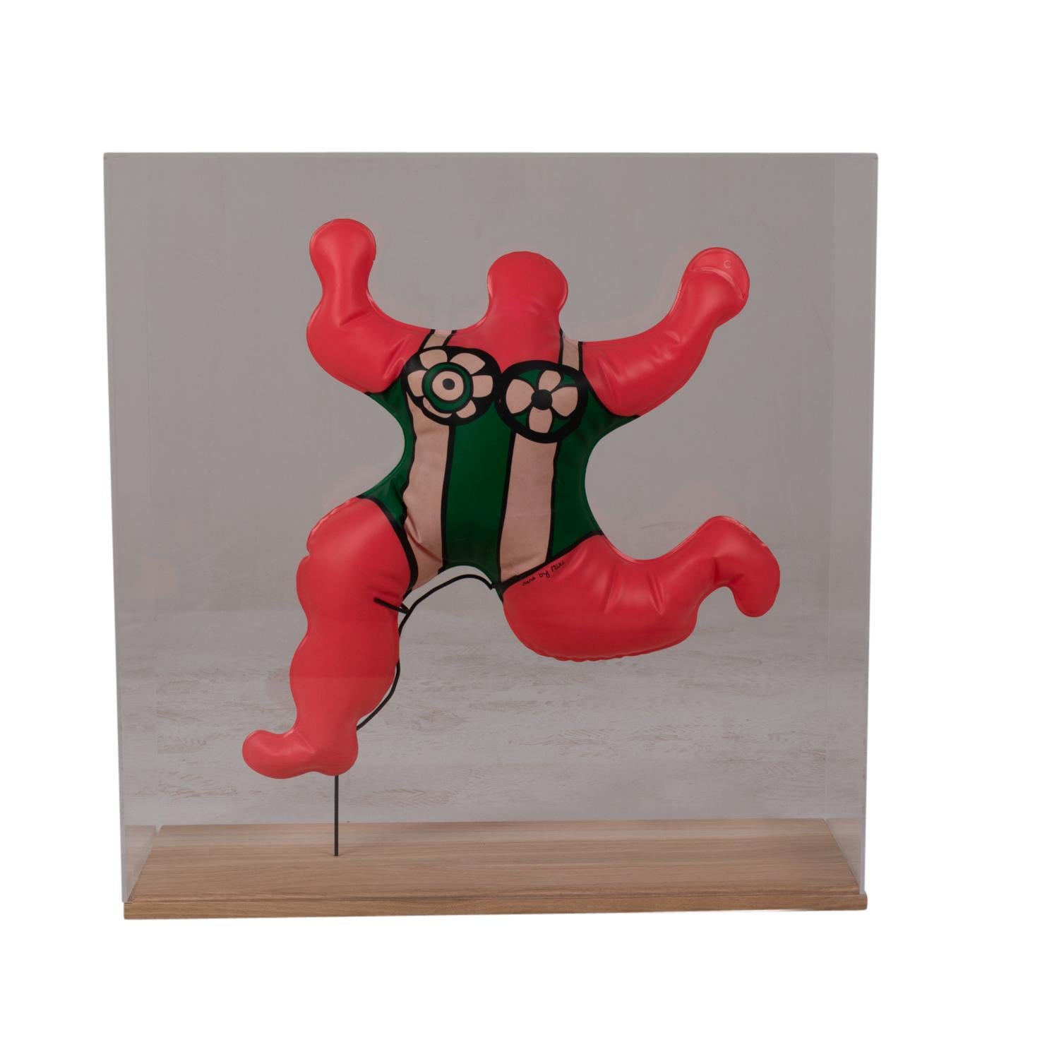 Niki de Saint Phalle for Flammarion, signed on the back.

Silkscreen printed in the form of an inflatable plastic doll, “Nana” model, displayed in its custom-made Plexiglas and blond oak base, with a tilting black lacquered metal rod.

French