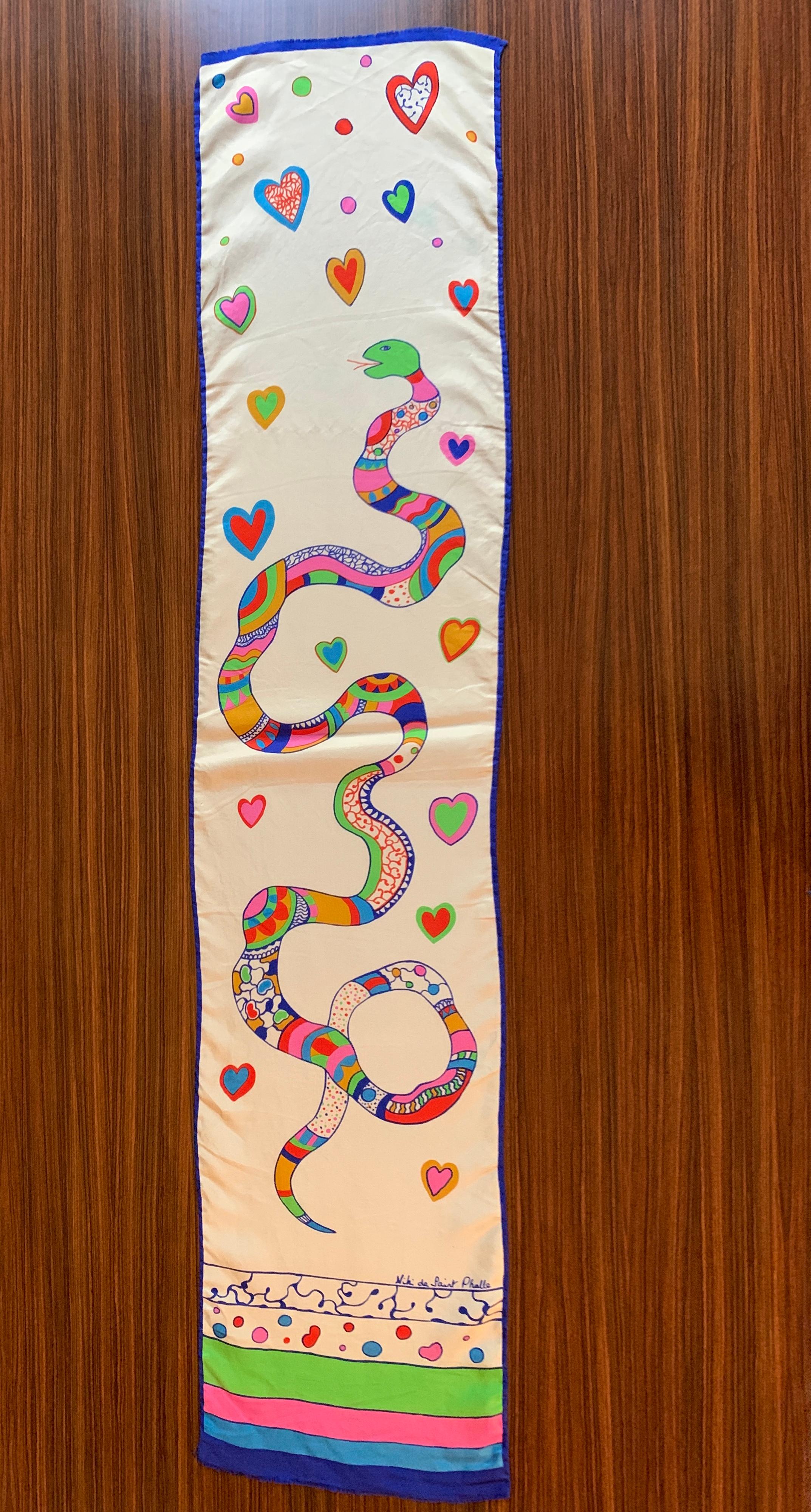 Cream and multicolor Niki de Saint Phalle silk scarf featuring one of Niki's signature snakes surrounded by hearts. Signed 'Niki de Saint Phalle