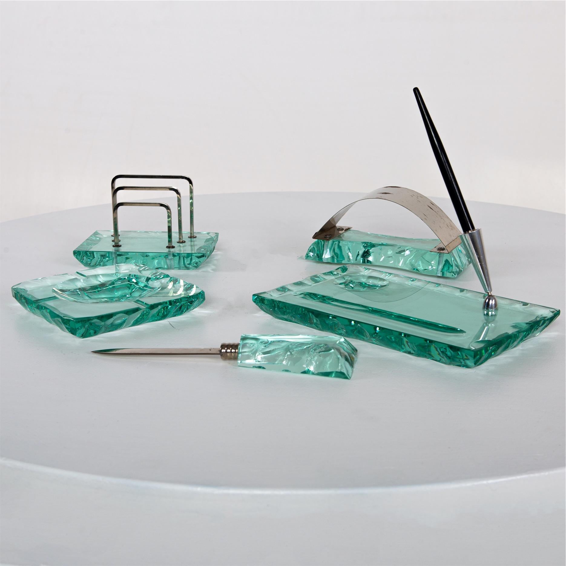 Desk set made of Nilo glass with rough edges in its original case. Included are a letter opener, pen and letter holder, ashtray and ink eraser. The case shows strong signs of age and use, the set is in very good condition.