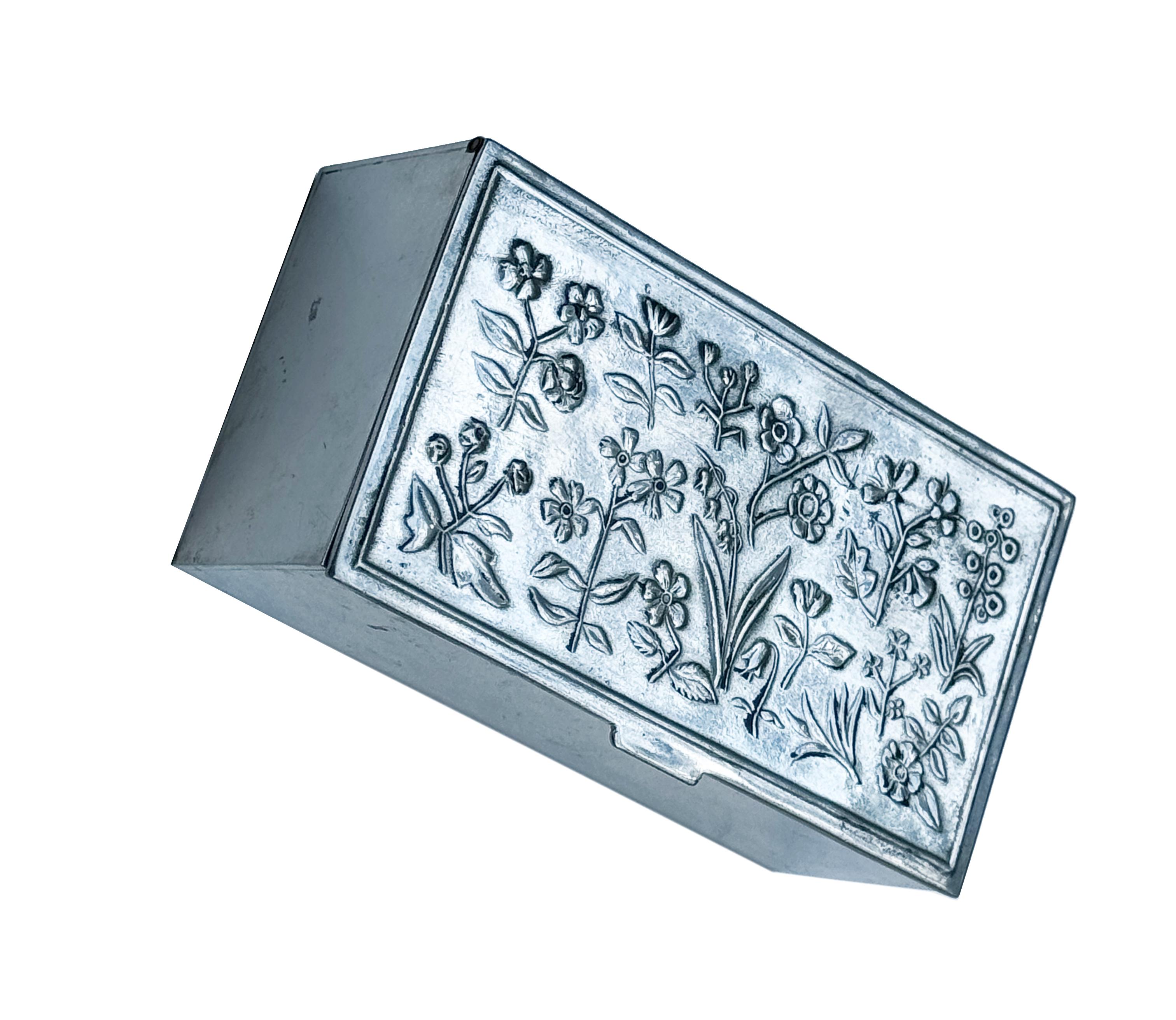 Nils Fougstedt (1881-1954), Caja de peltre  para Firma Svenskt Tenn, 1986
Se trata de una exquisita caja de hojalata adornada con intrincadas flores de prado en relieve. Los delicados motivos florales aportan un toque de belleza natural a la