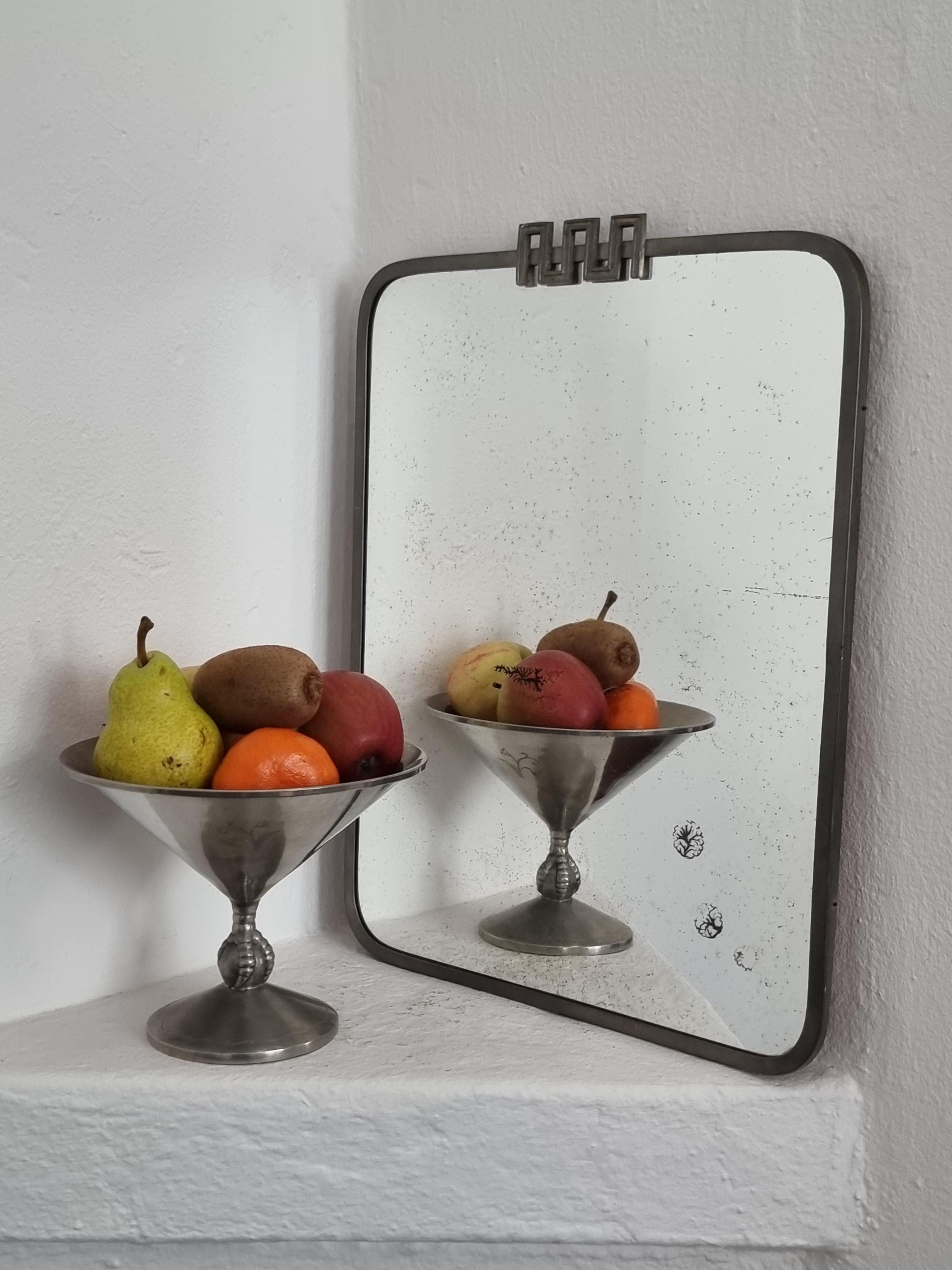 A decorative wall mirror by Nils Fougstedt for FAK / FAK Fabriksaktiebolaget Kronsilver, 1930s. Made in Sweden, Art Deco / Swedish Grace. 

The pewter frame is in good condition, with Hallmark FAK, Swedish Tin and H8=1934. 

The mirror glass has