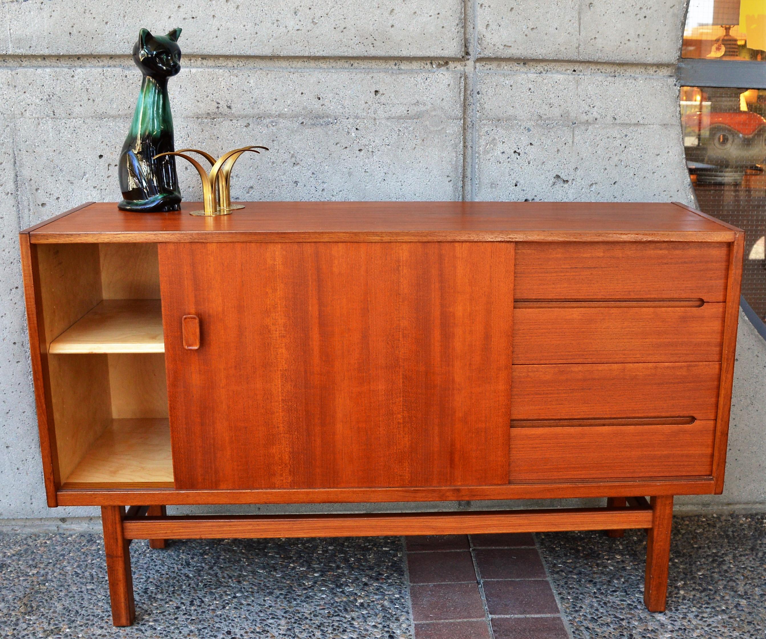 This nice smaller Danish modern all wood teak buffet / credenza was designed by Nils Jonsson for Troeds, 1960s, the Viken Model. The teak body with a lighter beech interior, features one slider with a sculptural teak door pull, which opens to reveal