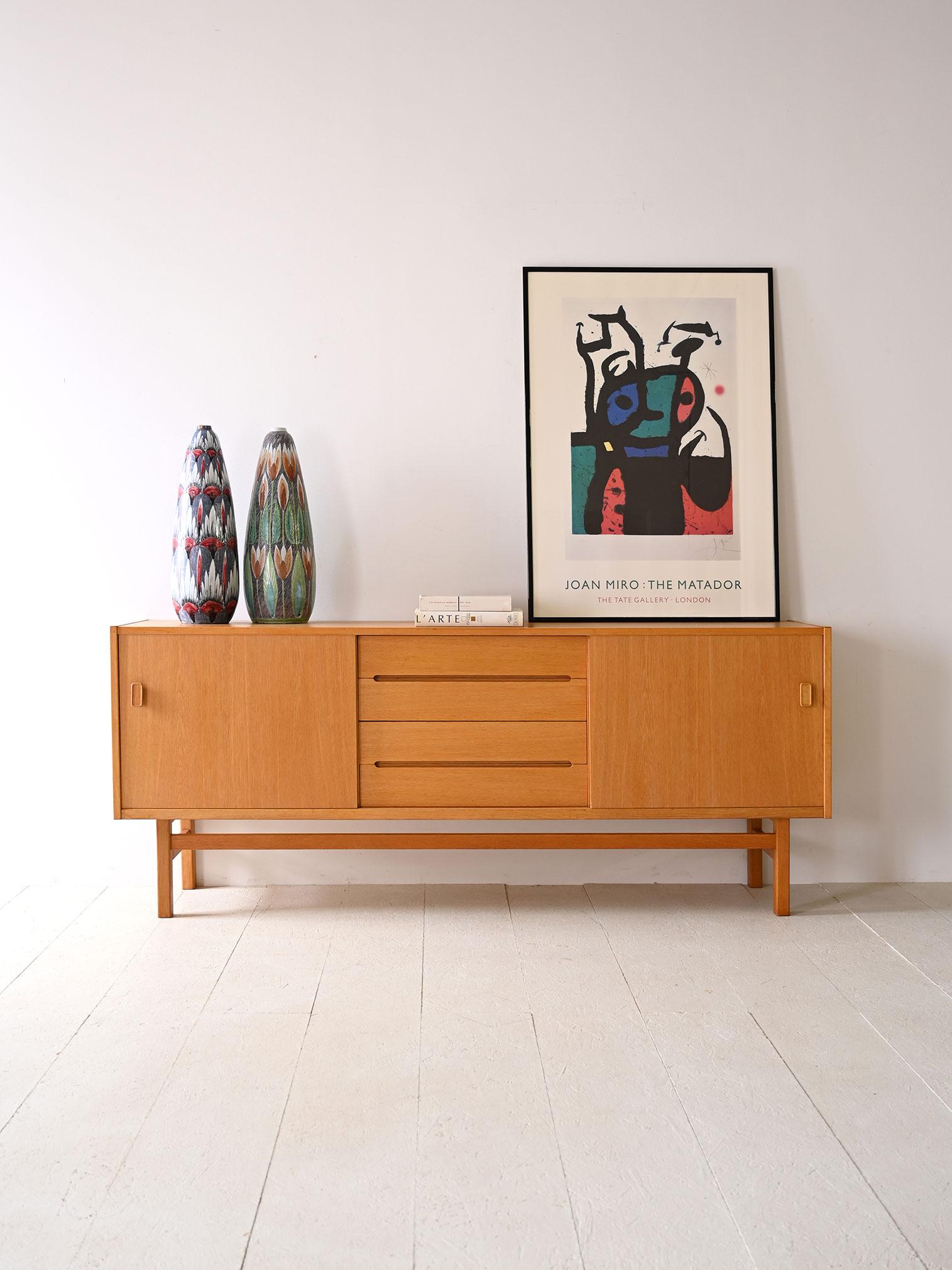Swedish original 1960s vintage sideboard. This elegant piece of Nordic modernist furniture is distinguished by its minimal lines and fine details. The structure respectively consists of a storage compartment closed by a sliding door and 4 central