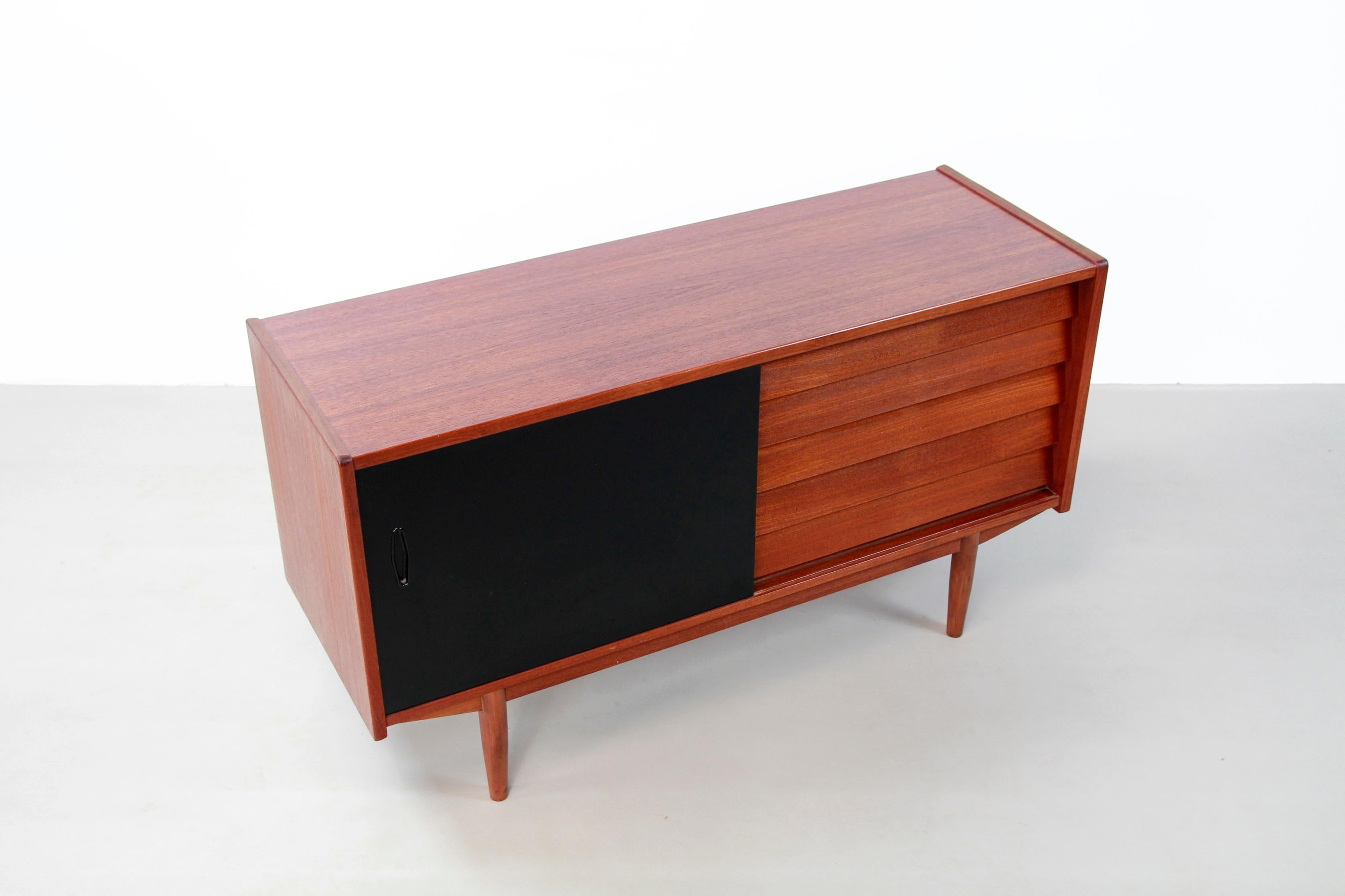 Swedish design sideboard designed by Nils Jonsson and produced by Hugo Troeds, Bjarnum. This minimalist sideboard with beautiful design comes from Sweden from the 1960s. The sideboard has an original black lacquered sliding door and five drawers.