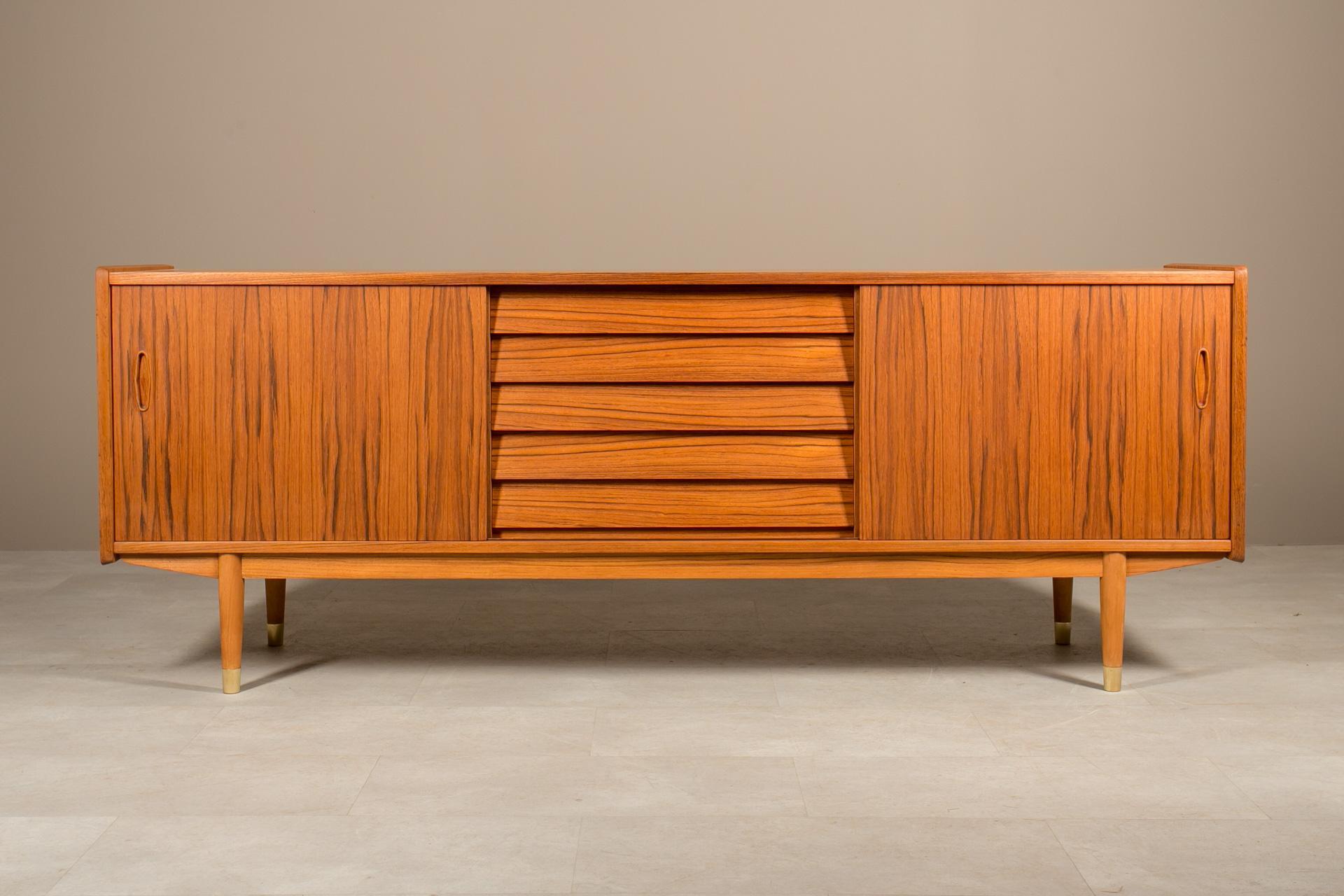 Scopri la squisita maestria di questa esclusiva credenza in legno di teak di Nils Jonsson, che vanta un caratteristico stile The Modern Scandinavian. Realizzata con precisione ed eleganza, presenta due ante scorrevoli su entrambi i lati,