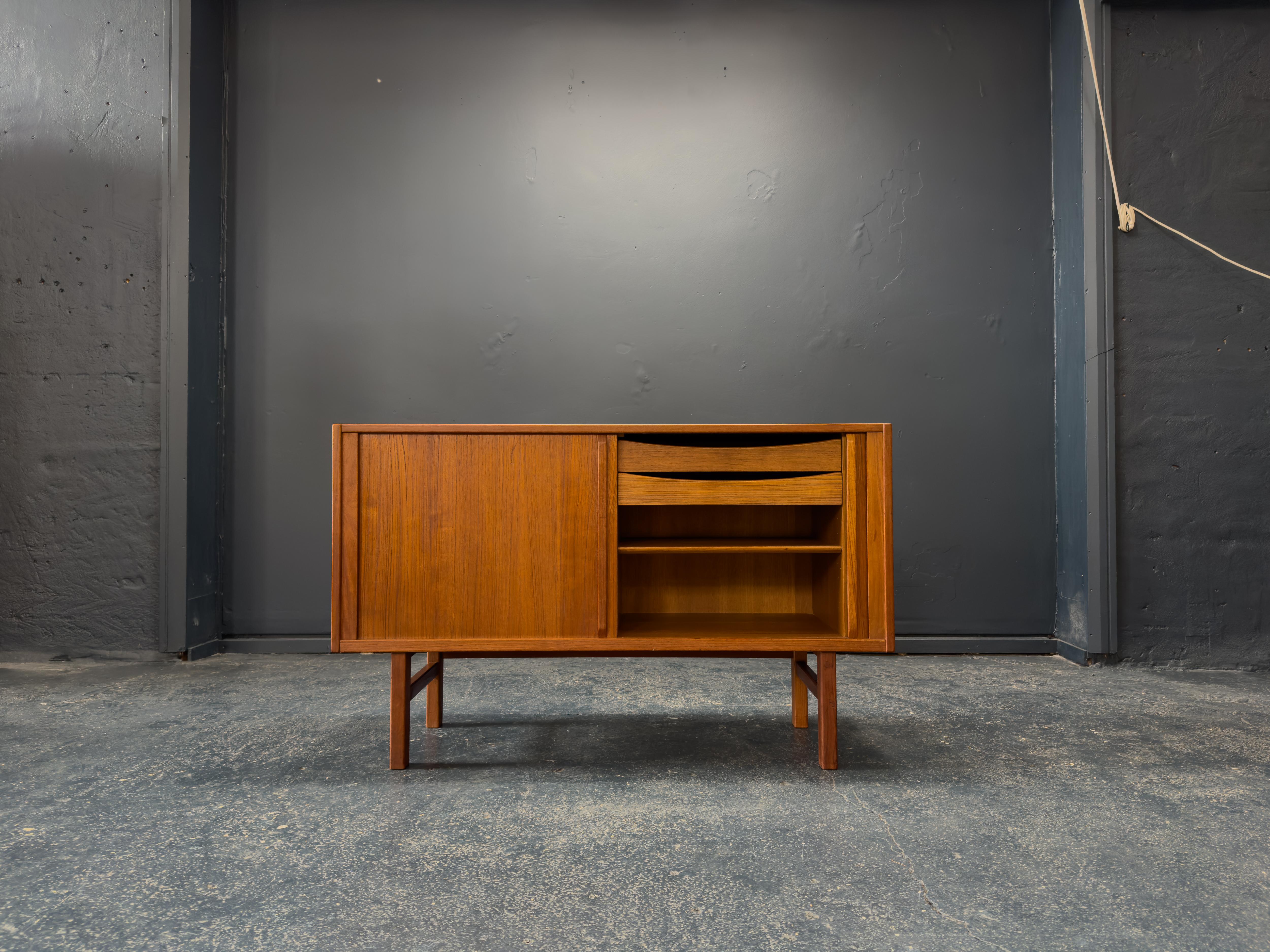 Esta pieza de bella factura es el mueble de pandereta Atle, diseñado por el célebre diseñador sueco Nils Jonsson para Troeds, Suecia, a mediados del siglo XX. Fabricado en rica y cálida madera de teca, el mueble muestra las líneas limpias y la