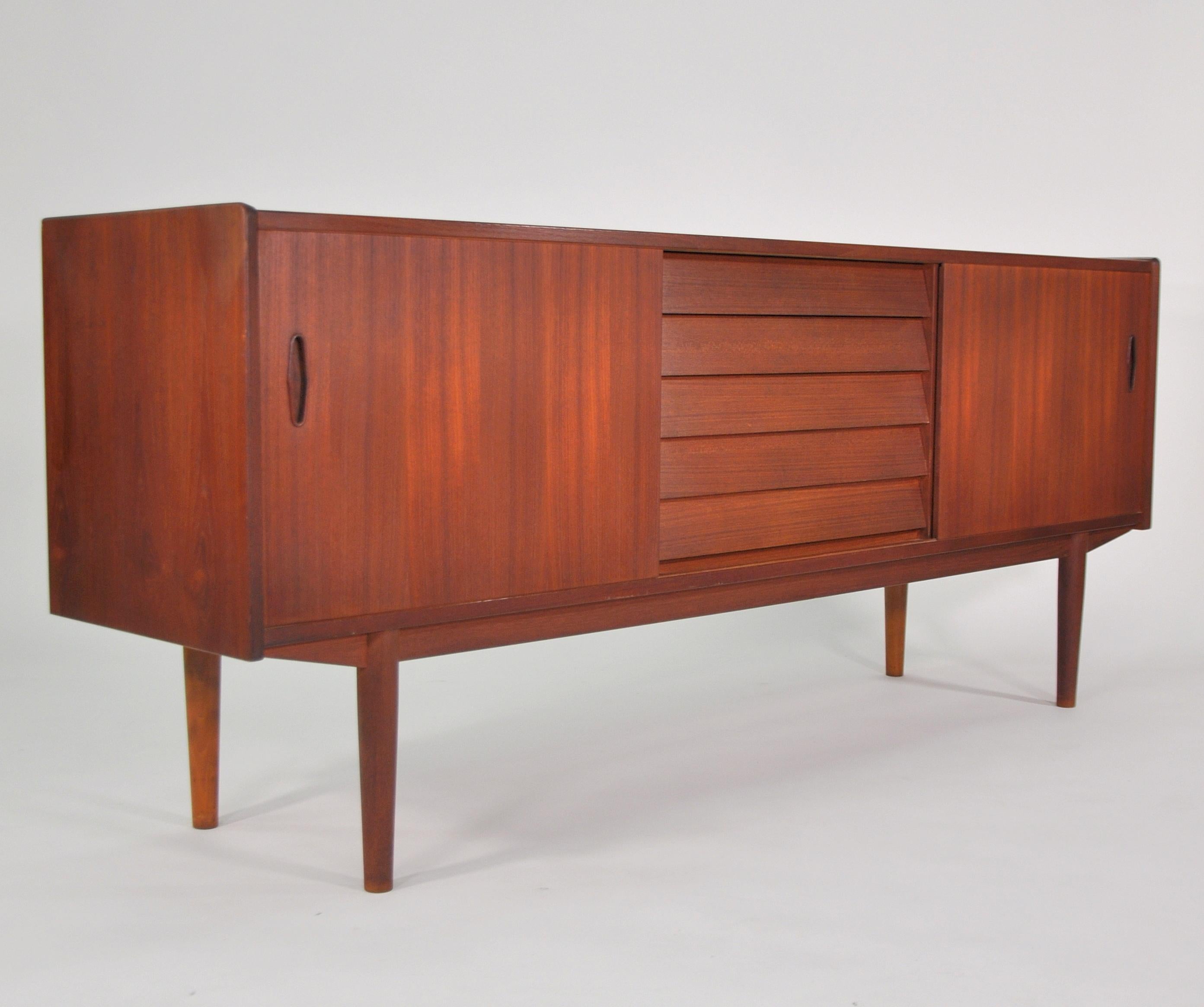 A gorgeous Mid-Century Modern trio cabinet designed by Nils Jonsson for Hugo Troeds, dating from the 1960s. The vintage sideboard features a pair of sliding doors, with a sculpted teak handle, opening to a cabinet space fitted with an adjustable
