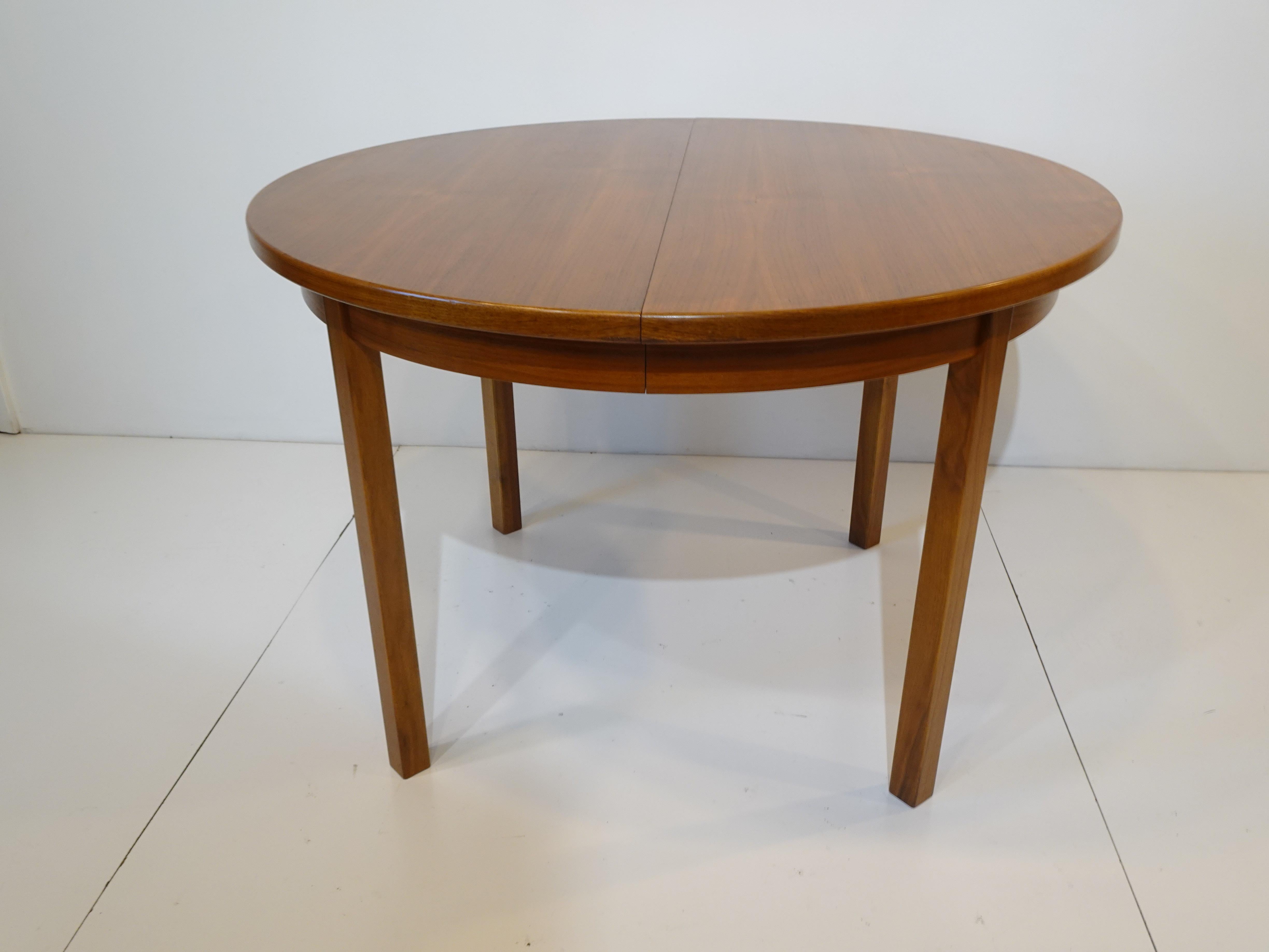 A walnut dining table with two folding leaves that can be stored under the top in a special built in holder, when used without the leaves it a round 43.13