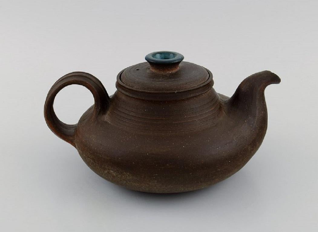Nils Kähler (1906-1979) for Kähler. Ceramic teapot with blue glazed lid knob. 
1960s.
Measures: 23 x 10.5 cm.
Signed.
In very good condition. Light wear on the spout.