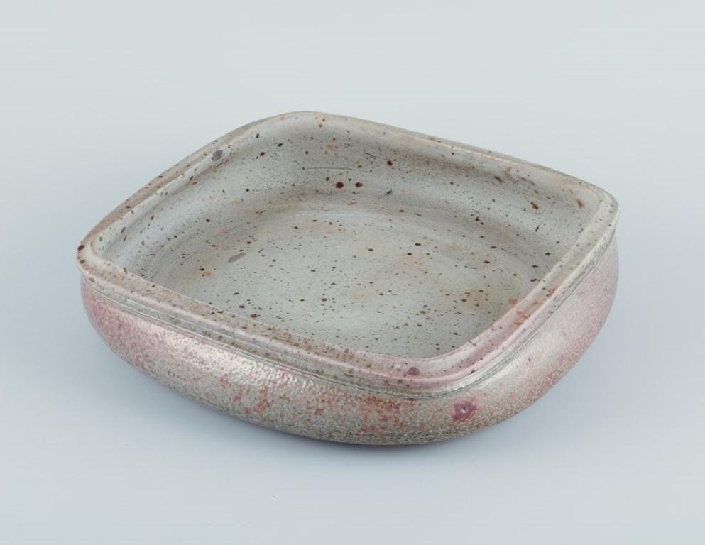 Nils Kähler for Kähler, ceramic bowl on four low feet.
Square shape. Glaze in earthy tones.
Approximately 1970.
Marked.
In good condition, small insignificant chip on top rim.
Dimensions: Diameter 25.0 cm x Height 5.5 cm.