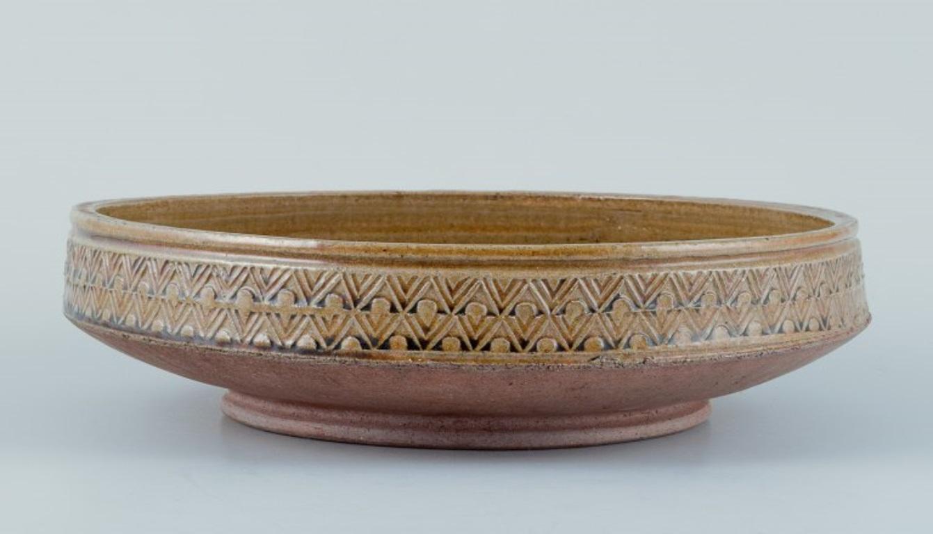 Nils Kähler for Kähler. Large ceramic bowl in a modernist design.
Uranium yellow glaze with a geometric pattern.
Approximately from the 1970s.
In perfect condition with natural crackling.
Marked.
Dimensions: Diameter 29.0 cm x Height 7.0 cm.