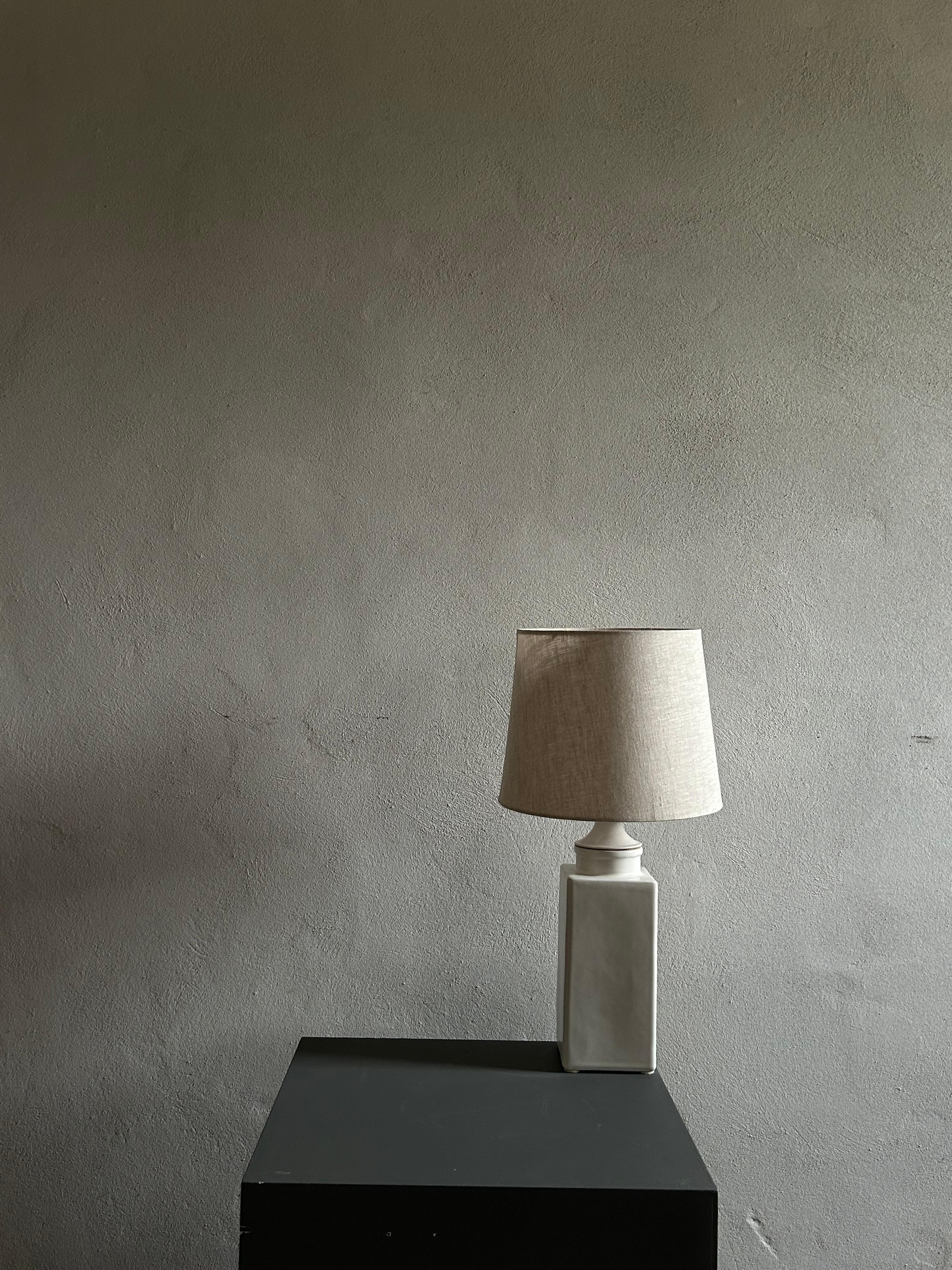 Une superbe lampe de table conçue par Nils Kähler dans les années 1960, qui met en valeur le savoir-faire artisanal et le design intemporel de l'atelier de céramique Kähler. Cette pièce présente un glaçage blanc minimaliste, mettant en valeur ses