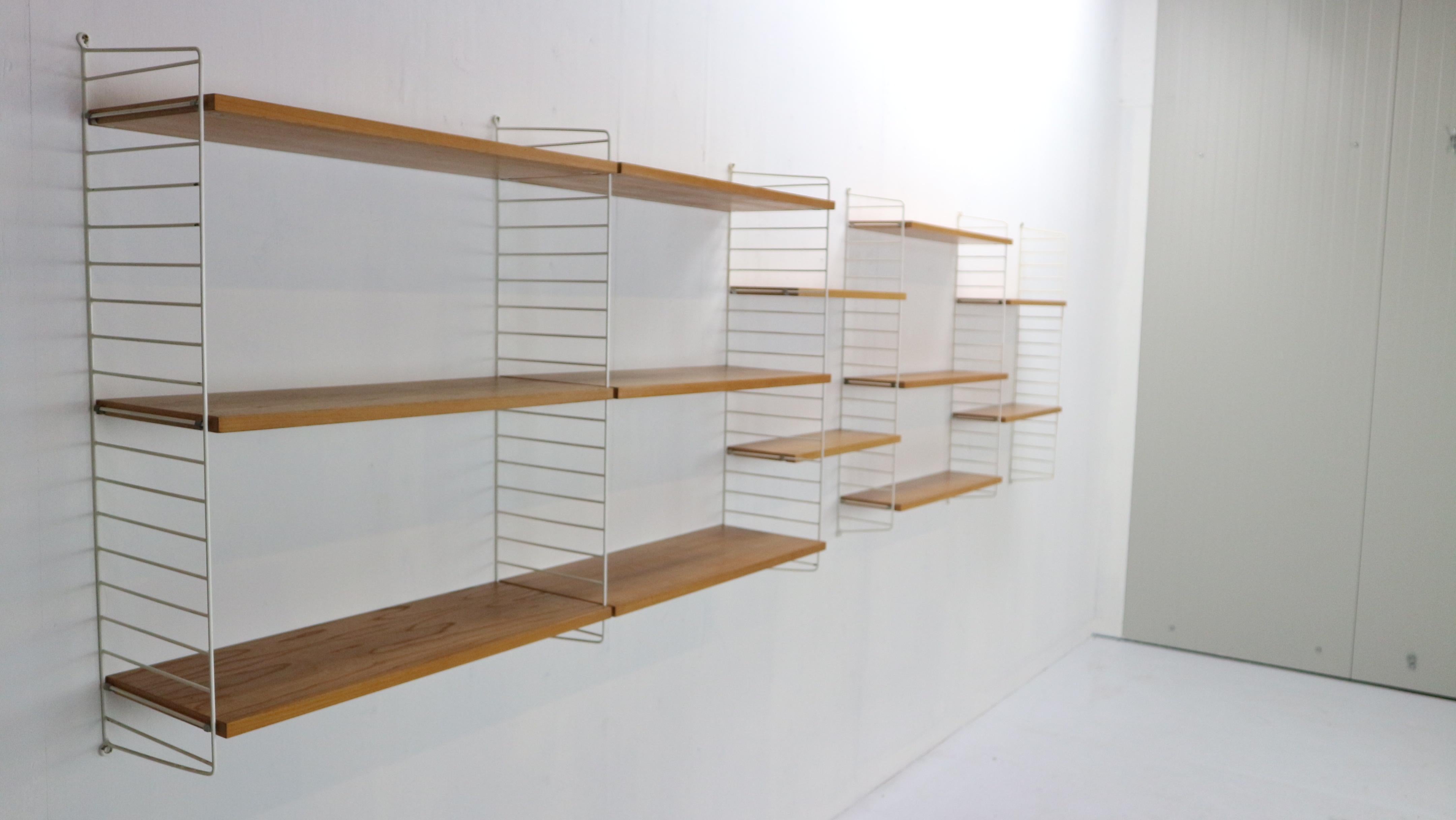 Extra large shelving system designed by Nils Nisse Strinning and manufactured by String Design in 1960s period, Sweden.
Minimalistic shelving united made from teak wooden shelves (13 pieces) and white metal uprights (6 pieces).
Shelves are easily