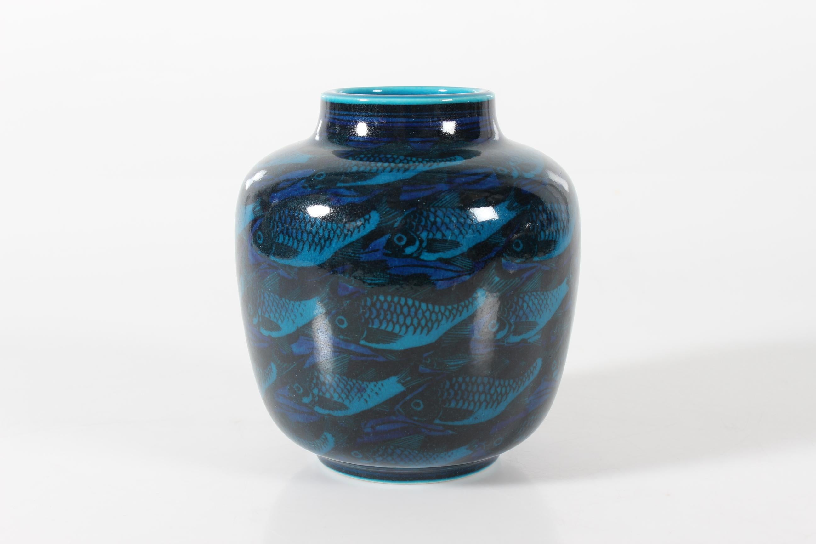 Blue bojan sharped jar vase model 21299 decorated with
turquoise blue, black and cobalt glossy glaze with fish motifs.

Fully marked on bottom with the Royal Copenhagen backstamp including the 3 waves and the initials of Nils Thorsson.
According to