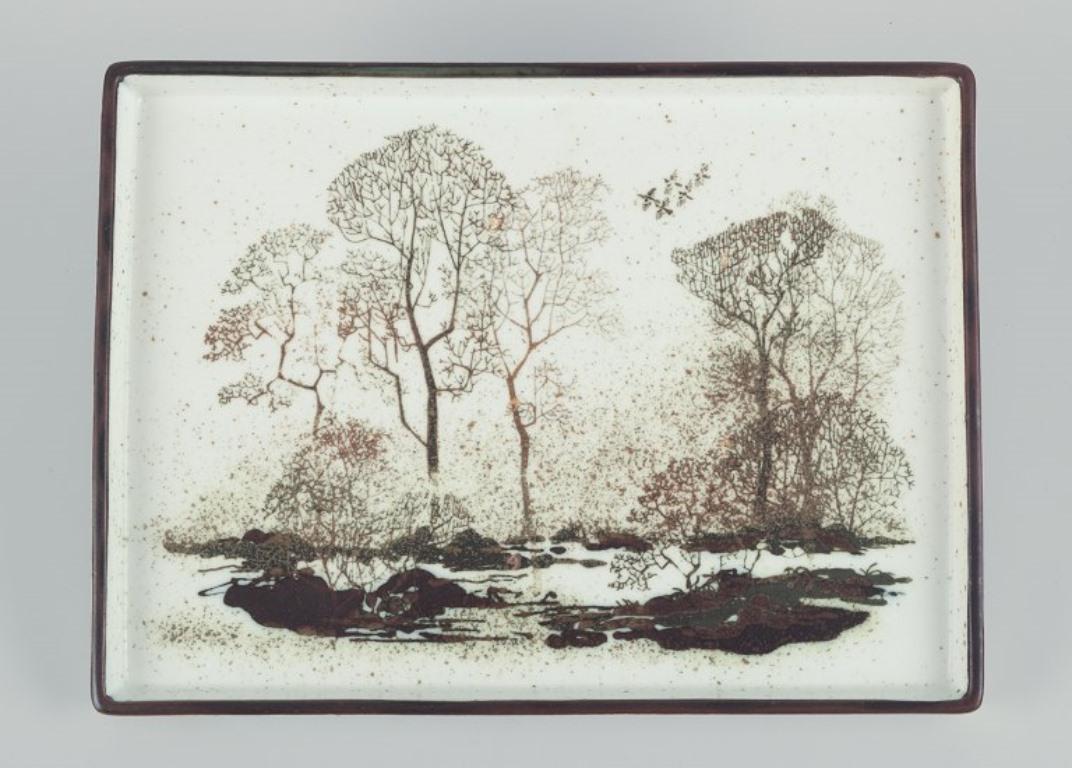 Nils Thorsson für Royal Copenhagen.
Keramiktablett mit Landschaftsmotiv aus Keramik. 
Datiert: 1975-1979
In perfektem Zustand.
Markiert.
Erste Fabrikqualität.
Abmessungen: Breite 29,5 cm. x Durchmesser 22,0 cm. x Höhe 2,0 cm.