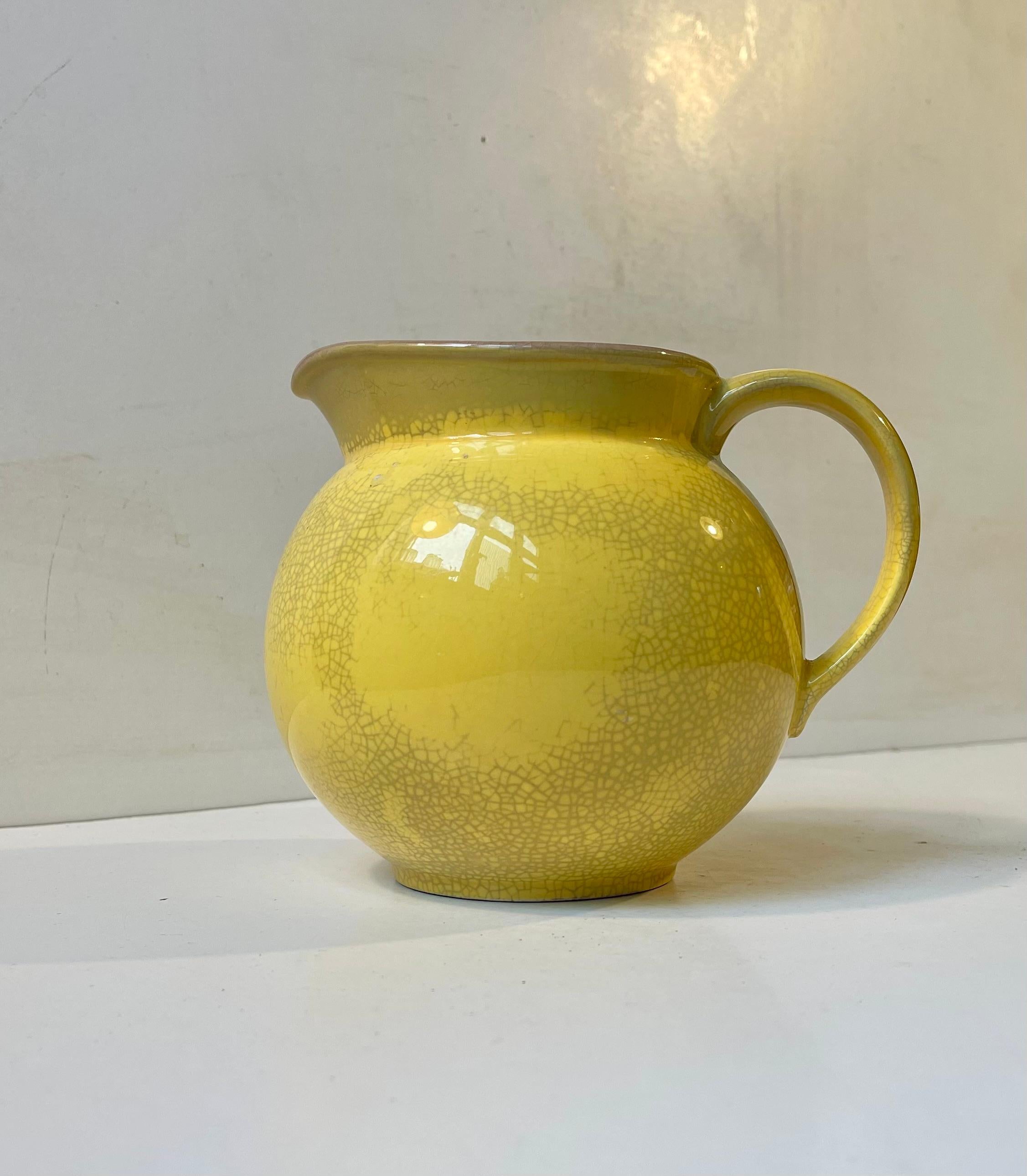 A rare yellow jug or milk pitcher designed by Nils Thorsson and manufactured by Aluminia in Denmark during the 1930s or 40s. Featuring a delicate crackle glaze to its interior. Its a predecessor to Confetti/sSusanne series. Marked to its base with