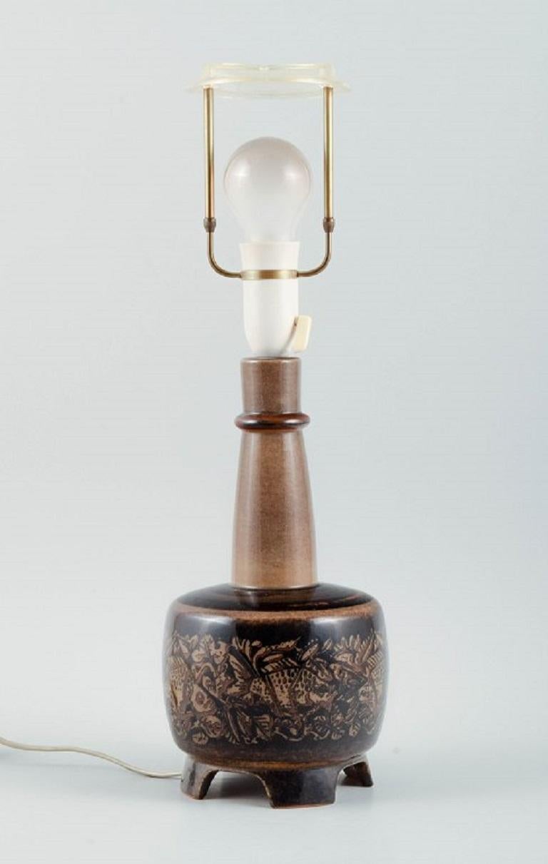 Nils Thorsson, geboren in Eslöv (1898-1975). 
Royal Copenhagen Porzellan Tischlampe auf vier Füßen montiert. 
Verziert mit Motiven in Form von Fischen in Braun, Schwarz und Rotbraun.
Signiertes Monogram, 21820, Royal Copenhagen.
Maße: Ohne