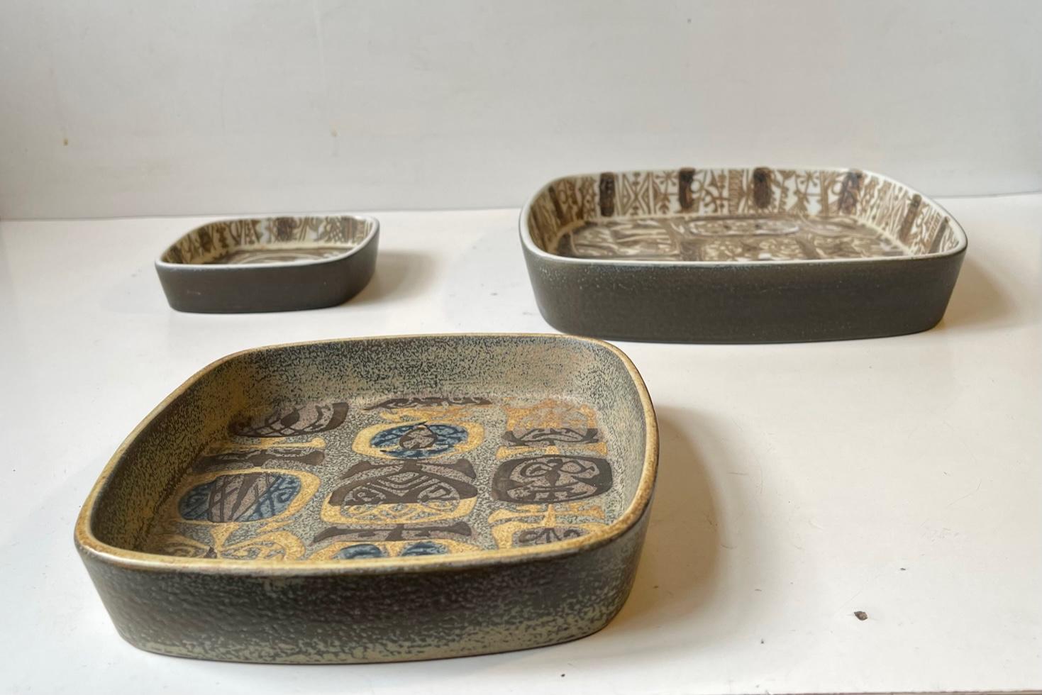 Royal Copenhagen ceramic Baca trays/dishes/small bowls designed by Nils Thorsson. Decorated in earthy glazes with an abstract motifs. All of them fully marked to the base with designer initials and makers mark. Measurements: W: 22.5/17/11 cm, H: