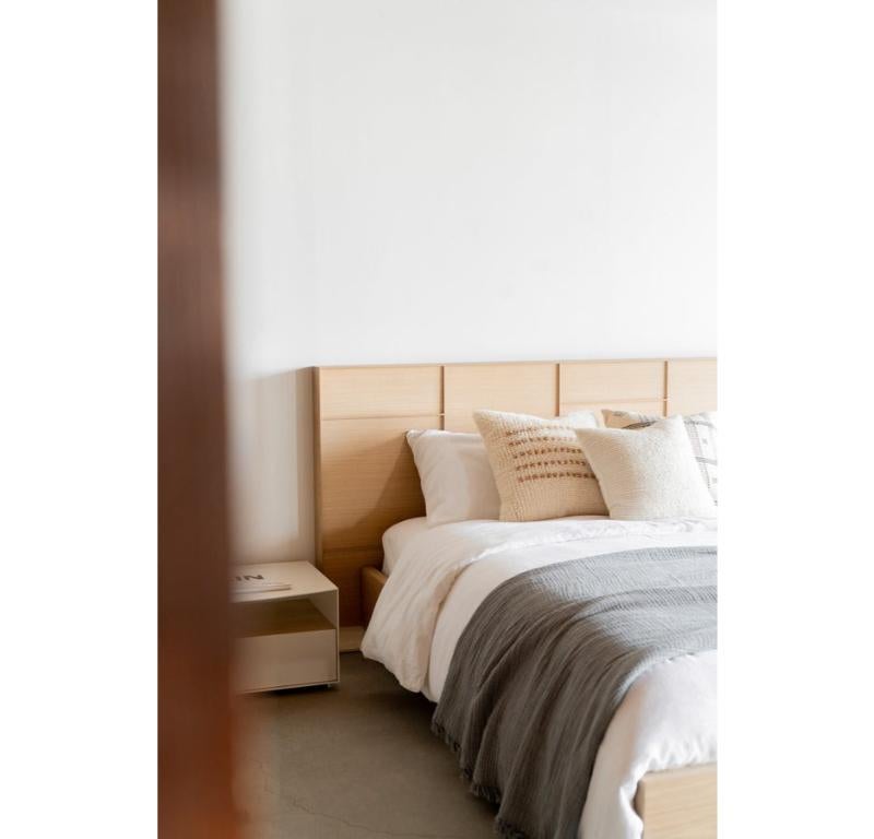 The Nima Bed features an oak headboard made up of asymmetric paneling, adding subtle detail to the surface of the piece. This feature, combined with the low profile footboard and side rails create a minimalist design. The solid oak side rails and
