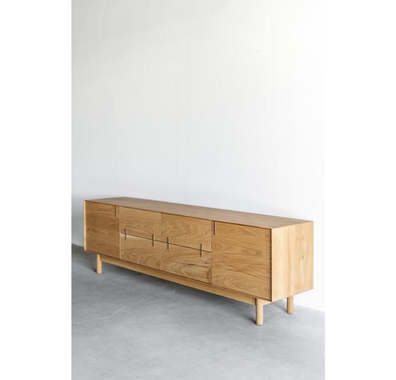The Nima Sideboard is handmade locally in Los Angeles, California. The oak casing has a thin profile that borders the drawers and doors beautifully. A walnut detail is featured on each face with push-release slides and hinges. The Nima Sideboard has