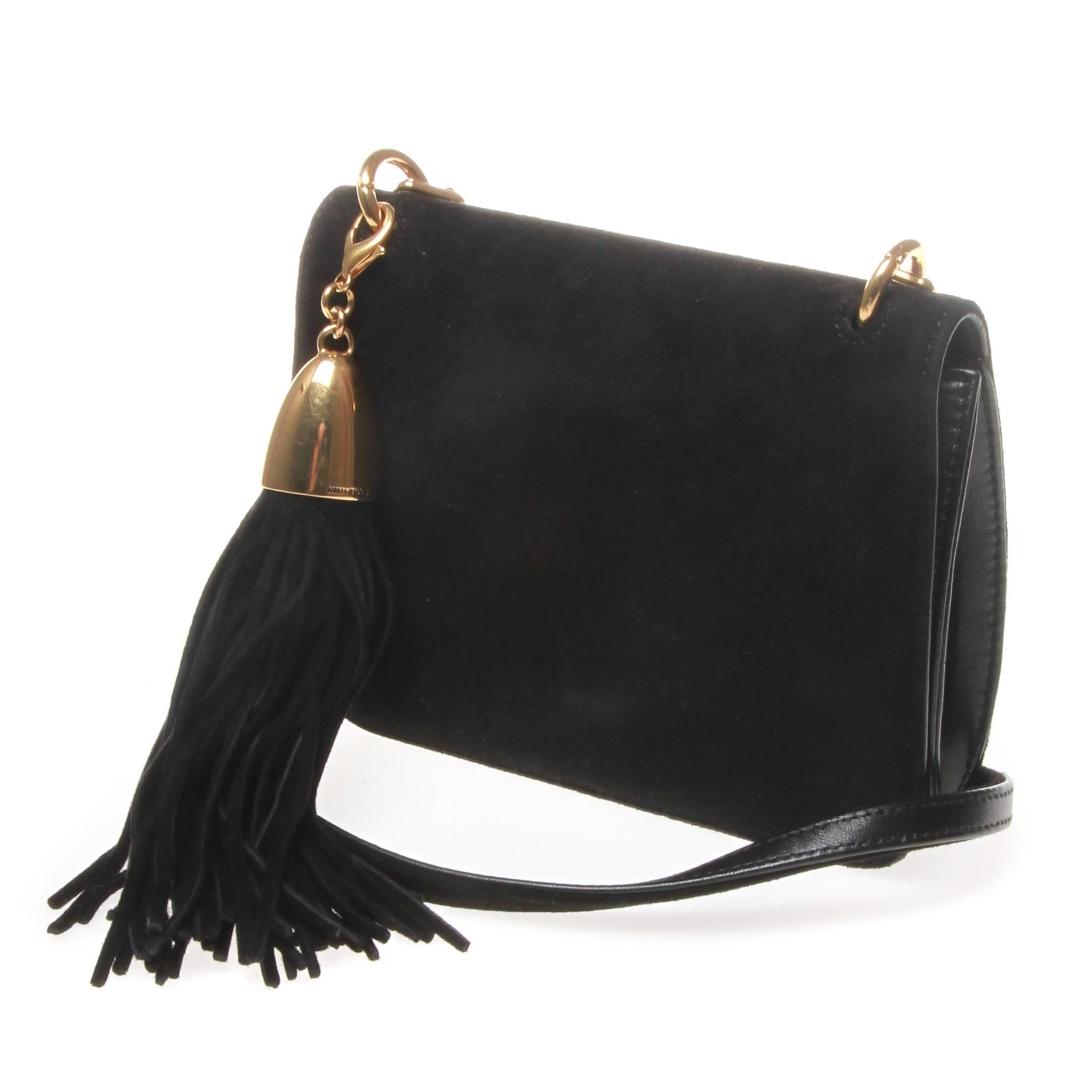 	
Nina Ricci mini shoulder bag in a black lambskin. One main pocket with a card slot sewn the puce coloured lambskin lining. Magnetic snap fastens the simple design with a thin suede and gold chain strap. Bag also features a clip on suede tassle.