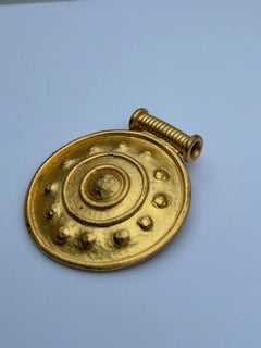 Spilla in metallo dorato stile bottone di Nina Ricci, firmata e datata C.C. 1985.