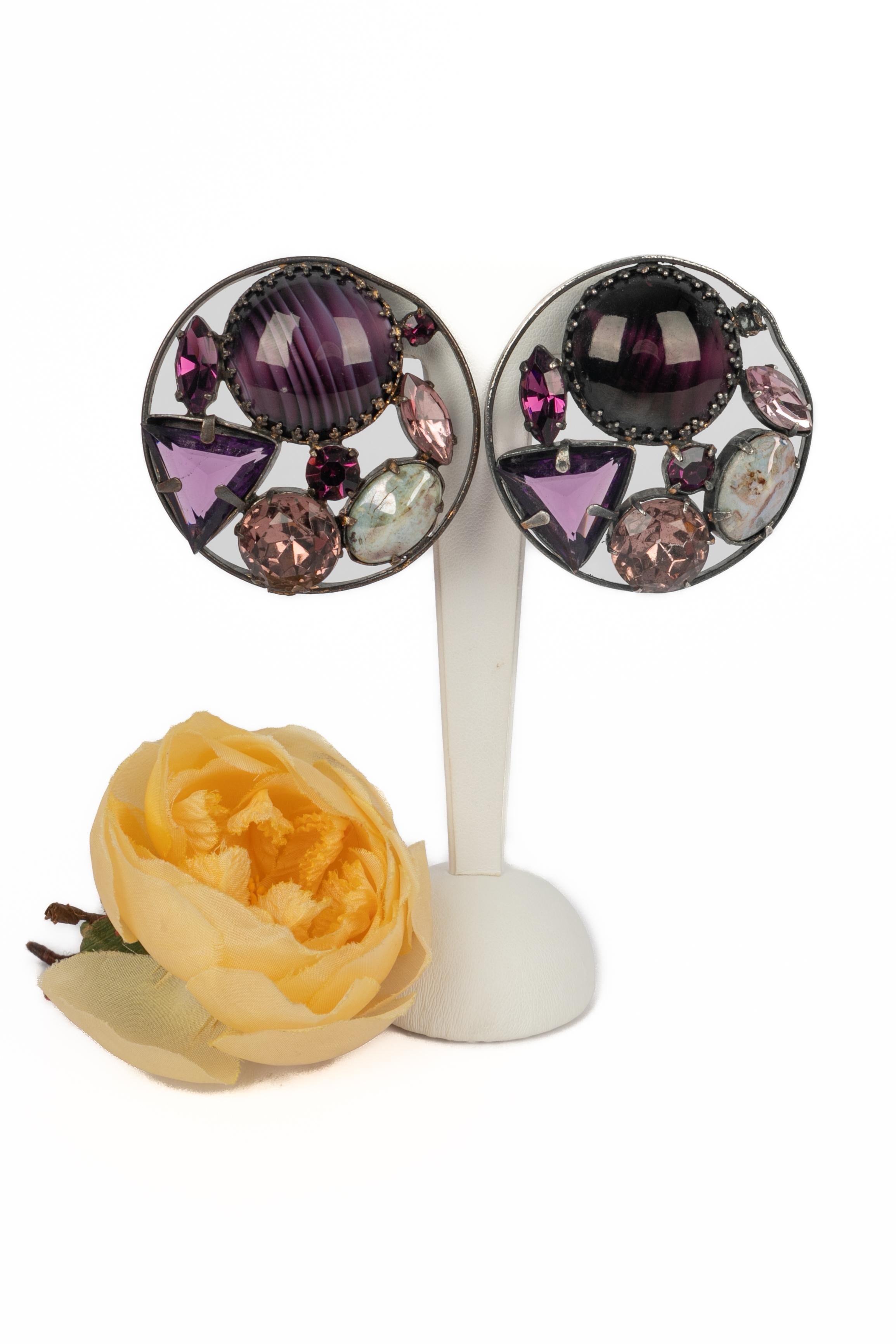 Nina Ricci - (Made in France) Orecchini a clip in metallo argentato scuro, decorati con strass viola e pasta di vetro.

Condizioni:
Buono stato

Dimensioni:
Diametro: 5 cm

SKU:BO66
