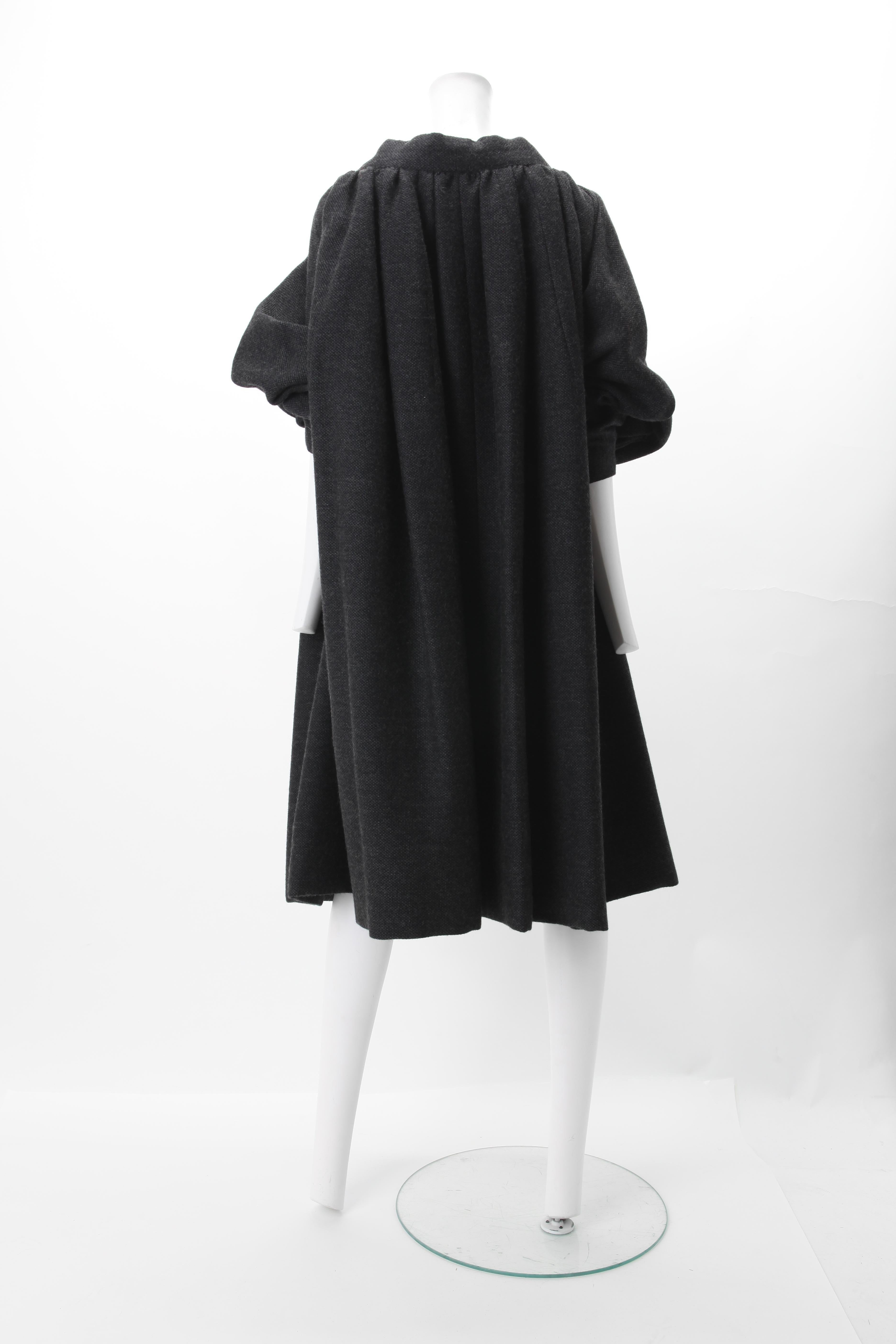 Nina Ricci Grey Wool Knit Cocoon Coat, c.1970s
1970s Nina Ricci Grey Cocoon Coat featuring boat neckline collar and tapered Raglan sleeves.
Three wooden button closure at center front.
Black Silk line Interior. 
Size: One Size