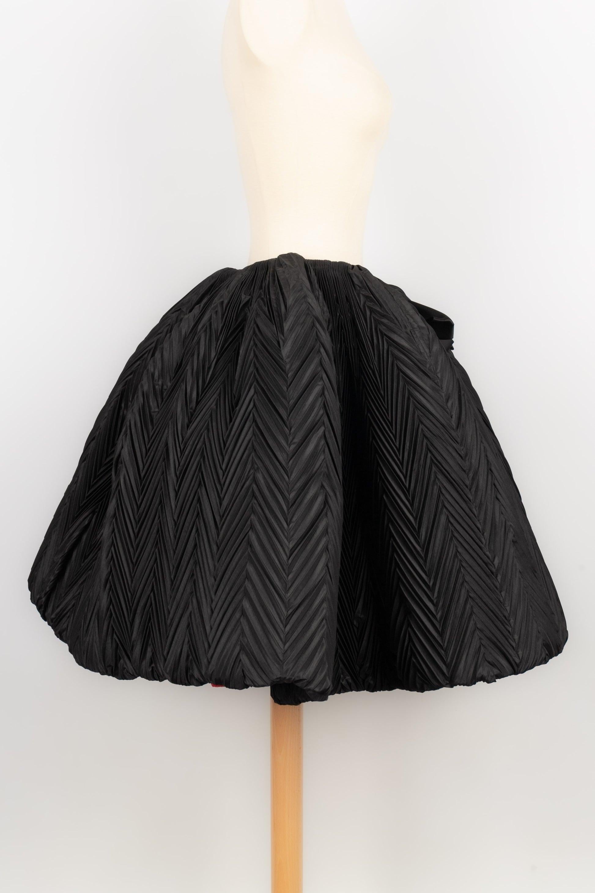 Nina Ricci -Haute Couture circle skirt covered with black taffeta with geometrical pleats and an impressive central bow. No size indicated, it fits a 36FR.

Additional information:
Condition: Very good condition
Dimensions: Waist: 30 cm - Length: 57