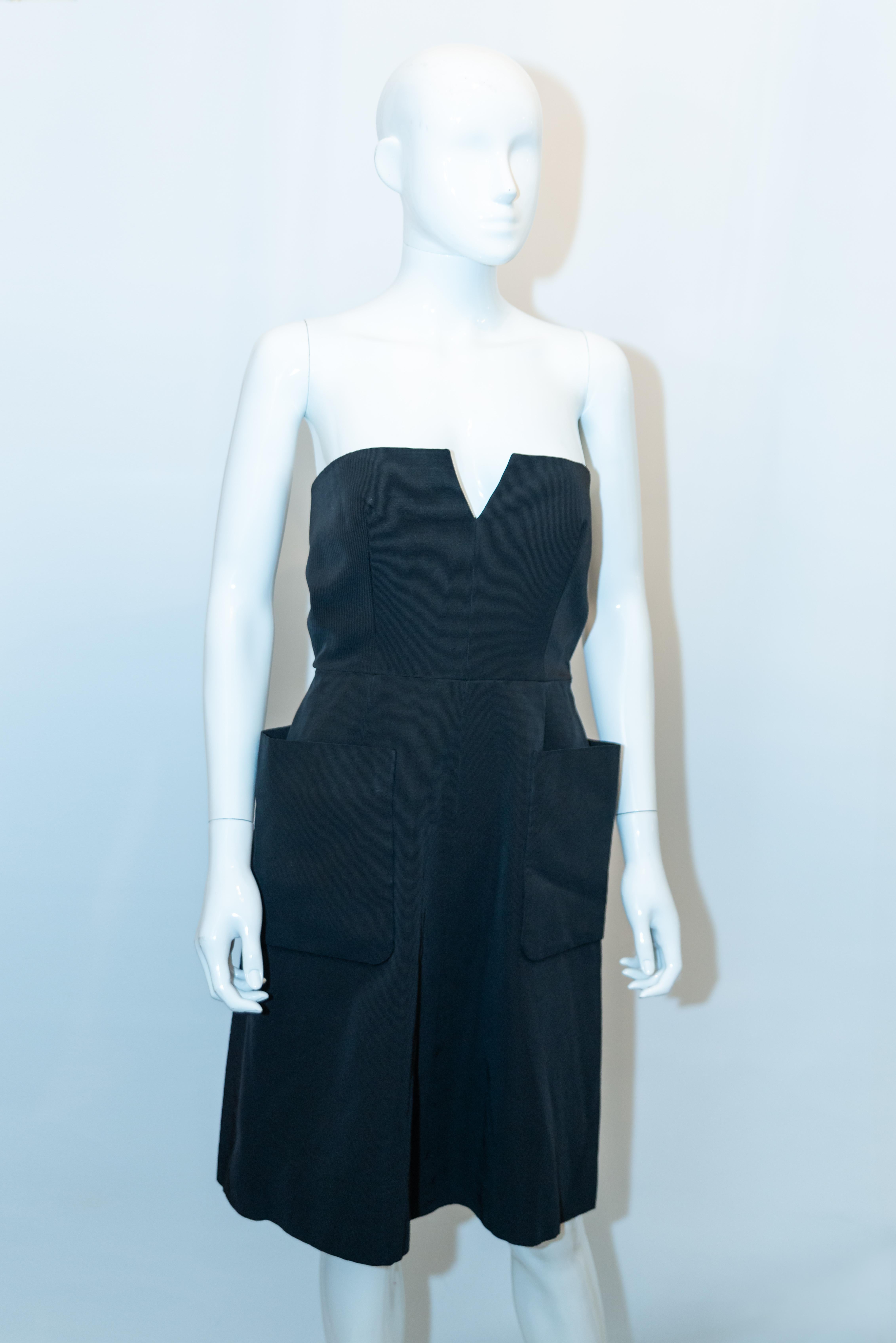 Ein schickes Cocktailkleid von Nina Ricci , Paris. Das Kleid aus schwarzem grobkörnigem Stoff ist trägerlos (Träger können leicht hinzugefügt werden),  mit zentralem Rückenreißverschluss, Miederstäbchen und Taschen auf der Vorderseite. Es ist