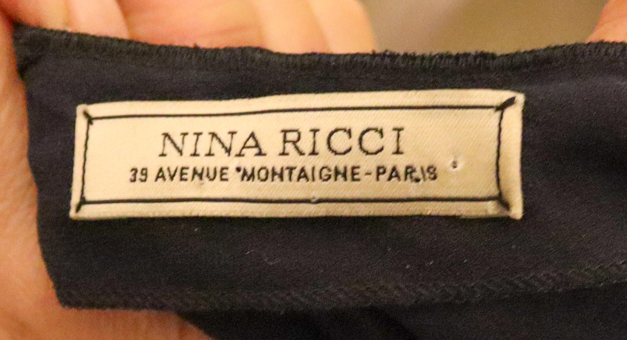 An elegant and interesting silk dress by Nina Ricci Paris. In a lovely shade of blue, the dress has a demure front with a pretty pleat and trim detail on the sleave. The back fastens at the neck and there is a large open area to the lower waist, all